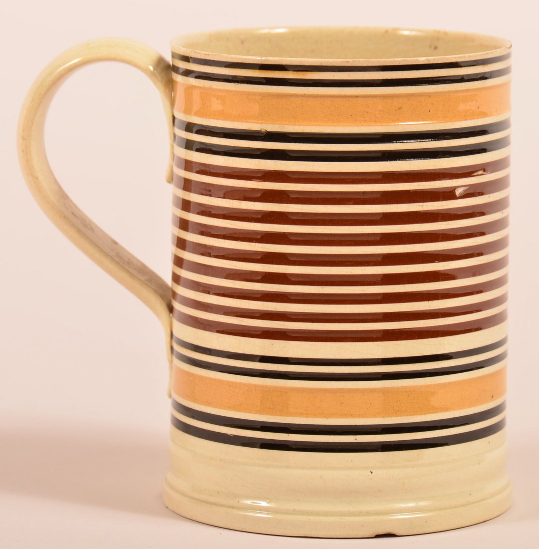 Early 19th Century Mocha Band Decorated Soft Paste: Early 19th Century Mocha Band Decorated Soft Paste China Mug. Tan, brown and black line and band design, applied loop handle with foliate ends. 4-1/4" high. Condition: Good with base chips.