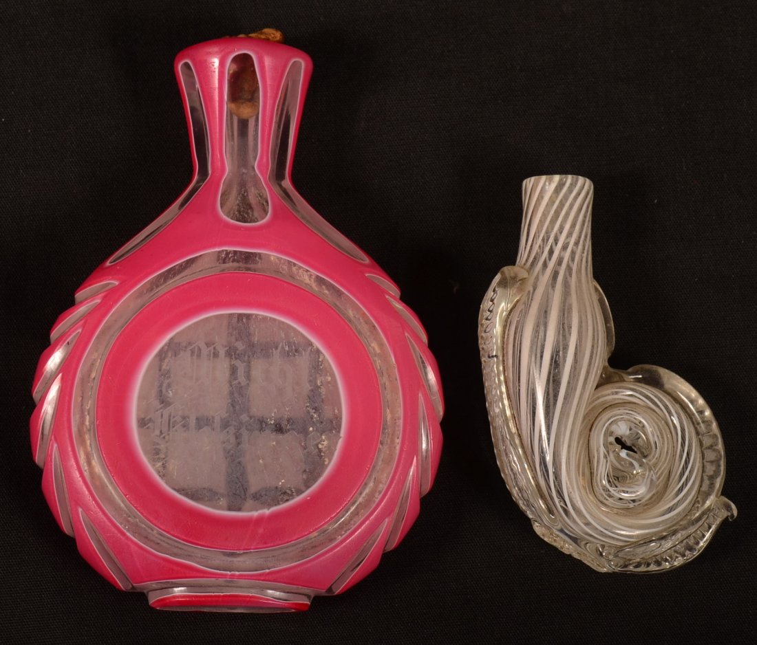 Two Glass Scent Bottles. 1st: Colorless Nailsea Snail: Two Glass Scent Bottles. 1st: Colorless Nailsea Snail Form with Applied Rib. 2-1/2"l. 2nd: Cranberry cut to clear disc form bottle with engraved name"Michl Klelsinger", 3-5/8"h. Condition: Good.