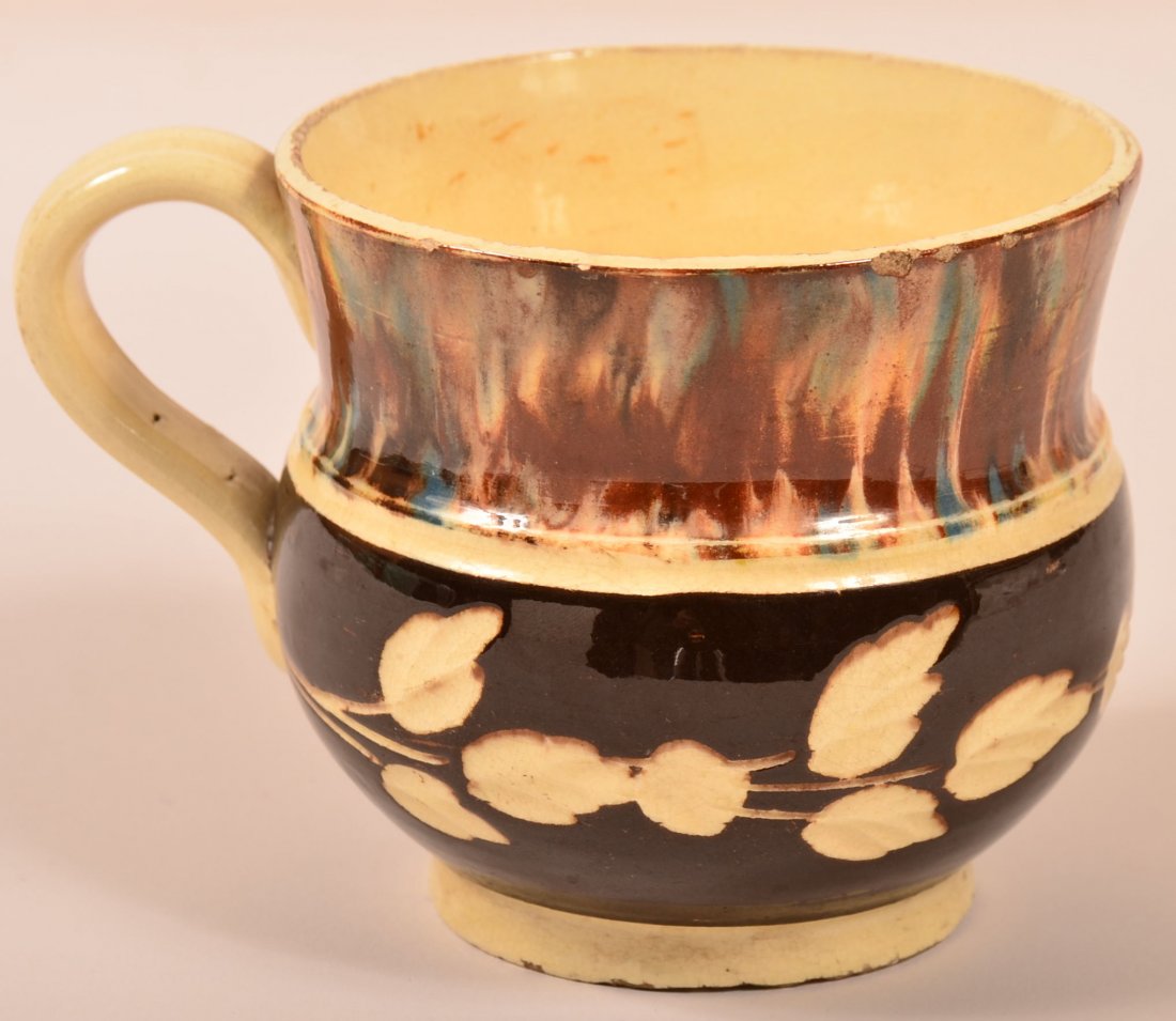 Mocha Decorated Glazed Earthenware Mug with brown cut: Mocha Decorated Glazed Earthenware Mug with brown cut to cream foliate decorated lower band. 3-1/2"h. Condition: Good, some rim chips.