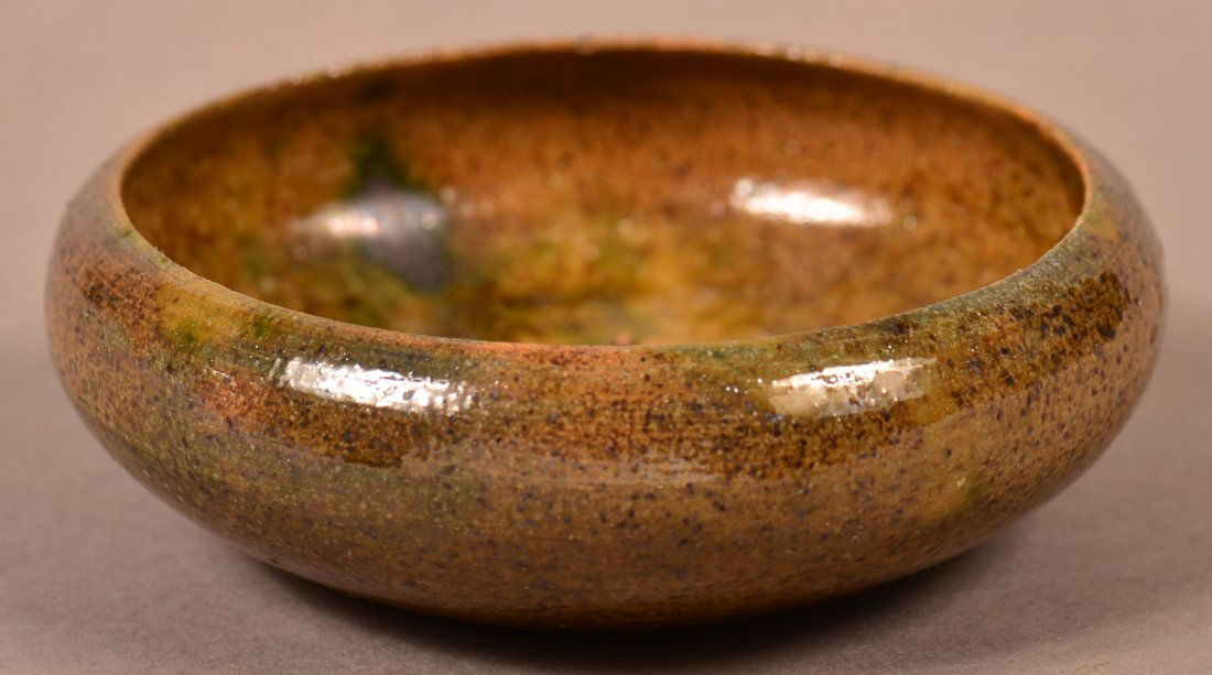 George E. Ohr Glazed Redware Pottery Salt.: George E. Ohr Glazed Redware Pottery Salt. Stamped signature on bottom "G. E. OHR, BILOXI". Mottled glazed round form salt with rolled shoulder. 3-1/8" diam. Condition: Very good with couple of pin ni