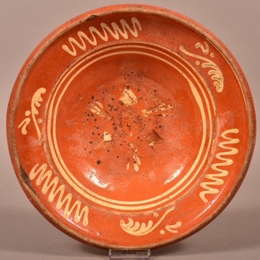 Yellow Slip Decorated Redware Pottery Bowl.: 19th Century Yellow Slip Decorated Redware Pottery Bowl. Center with floral and foliate decoration, shoulder with sprig and zig zag decoration. 12" diam. Condition: Fair with rim chips and losses to d