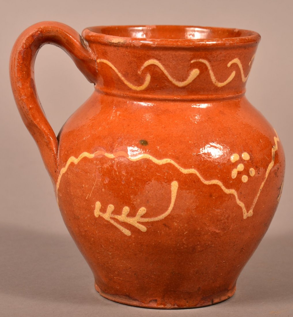Yellow Slip Decorated Redware Bulbous Mug.: 19th Century Yellow Slip Decorated Redware Pottery Bulbous Mug. Floral, sprig and zig zag yellow slip decoration. 6-1/4"h. Condition: Fair to good, some chips and glazing loss.