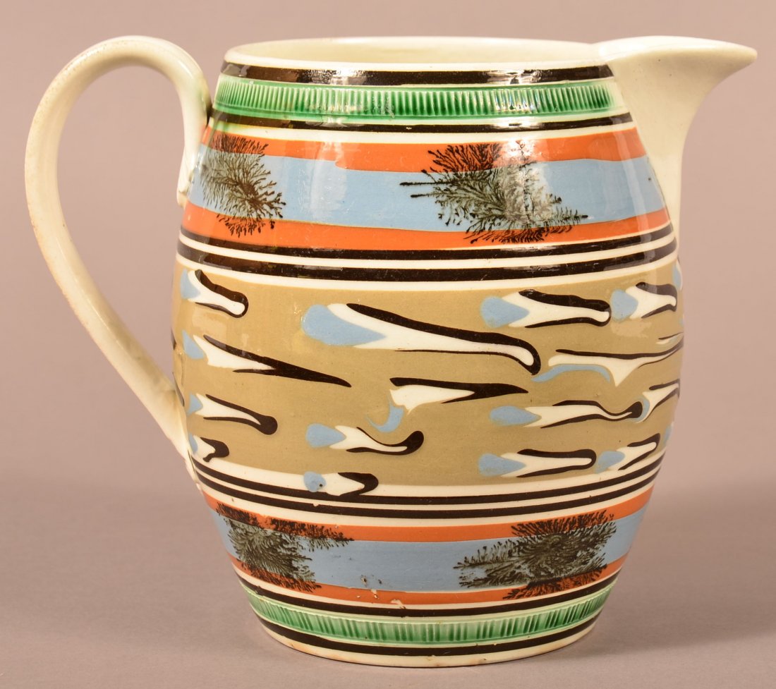 Outstanding Mocha Decorated Pitcher: Mocha Decorated Soft Paste China Pitcher. Decorated with very strong bold colors of trailing cats eye, seaweed, and green bands. 6 3/4"h. Condition: Good with professional restoration to spout and chi