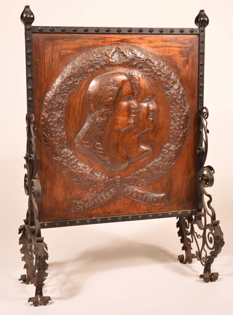 Arts and Crafts Period Fire Screen.: Arts and Crafts Period Iron and Sheet Copper Fire Screen. Ornate wrought iron frame with embossed copper panel with profile of a man and a woman inside acorn wreath, signed in bottom banner "Schiller