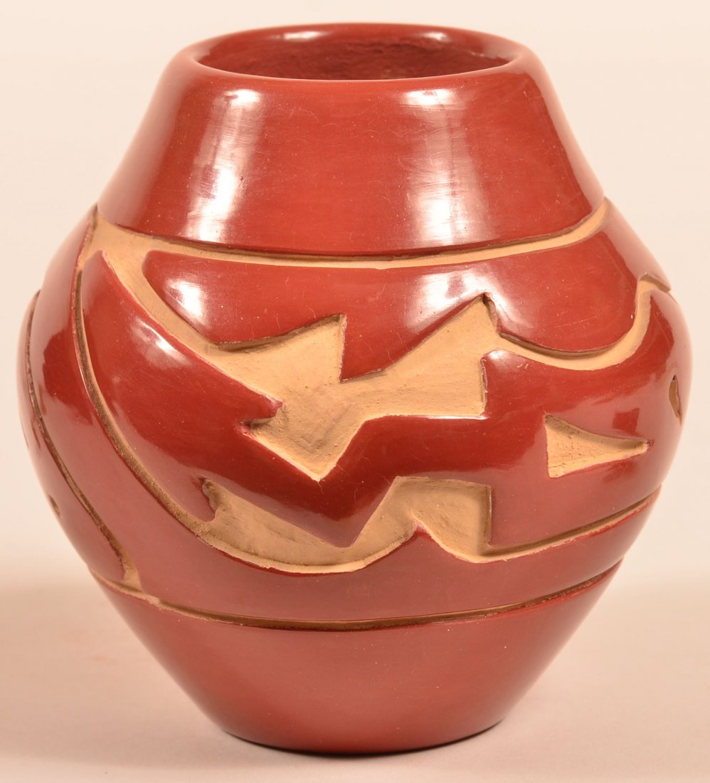 Pot by Stella Chavarria: b. 1939 Santa Clara. Signed. Carved red pot with clouds, water and Avanyu (water serpent) The small hole in the lower side is the spirit path. The majority of Stella's pots are carved black. Carved re