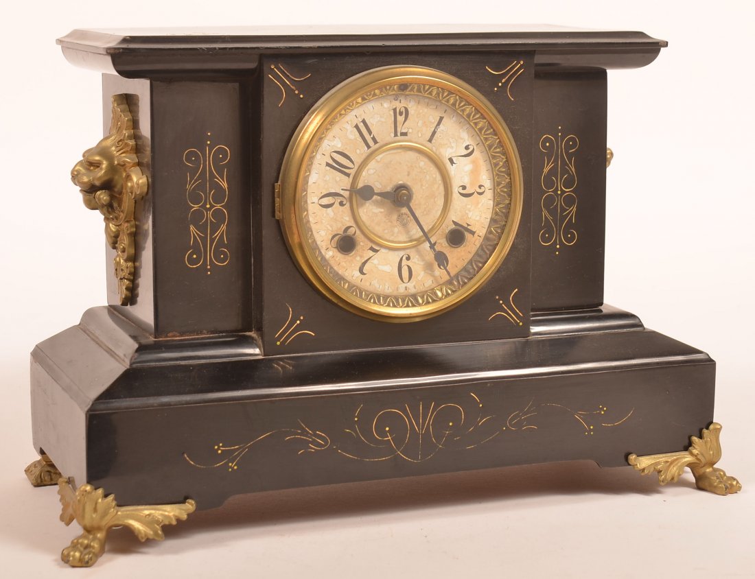 New Haven Enameled Metal Case Mantel Clock.: New Haven Black Enameled Metal Case Mantel Clock. Gilt metal lion head handles and paw feet. 10-3/4"h. x 16"w. x 7-1/4"d. Condition: Good with minor wear and scratches, some foxing to dial, no key.