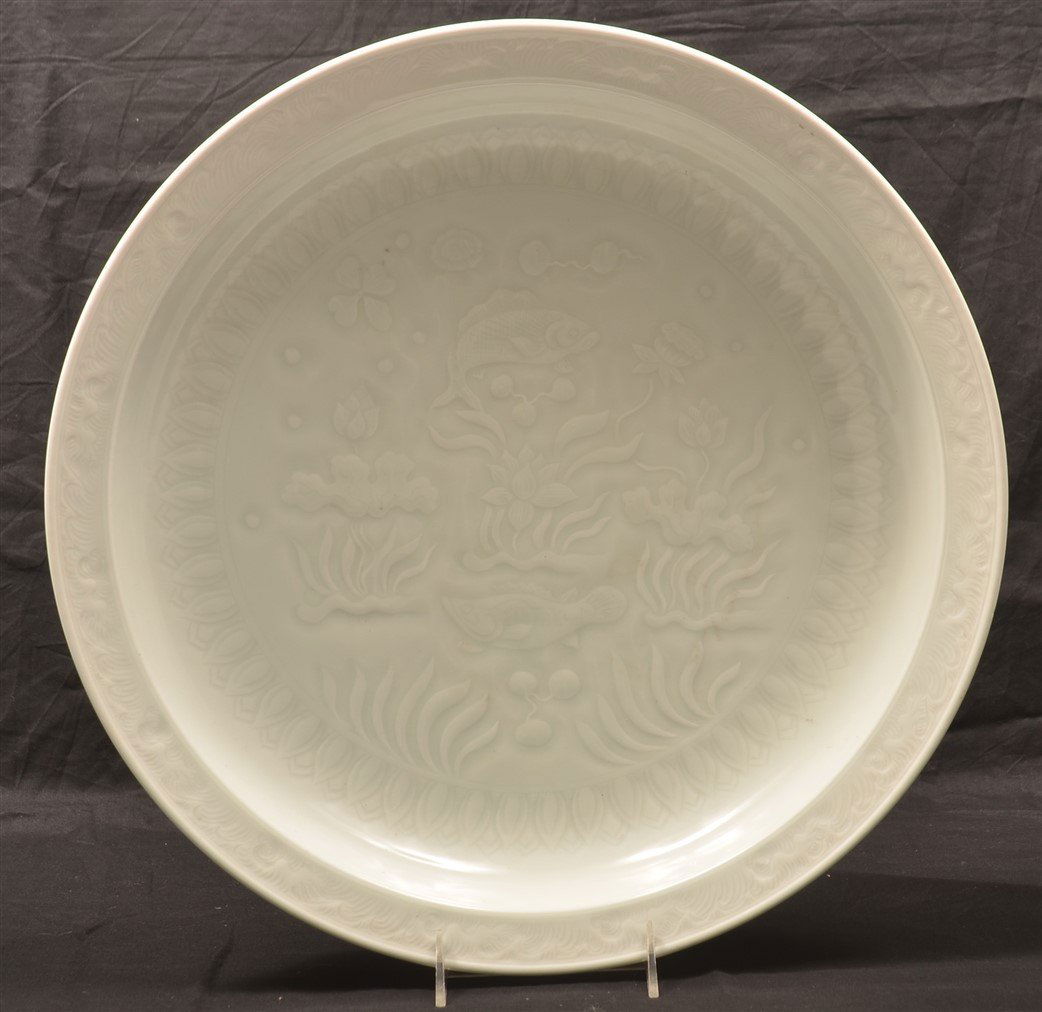 Antique White Celadon Porcelain charger.: Antique Chinese White Celadon Porcelain charger. Incised Chinese two character mark. Carved central design of fish and water plants, cavetto with central roundel of a lotus, border with wave decoratio