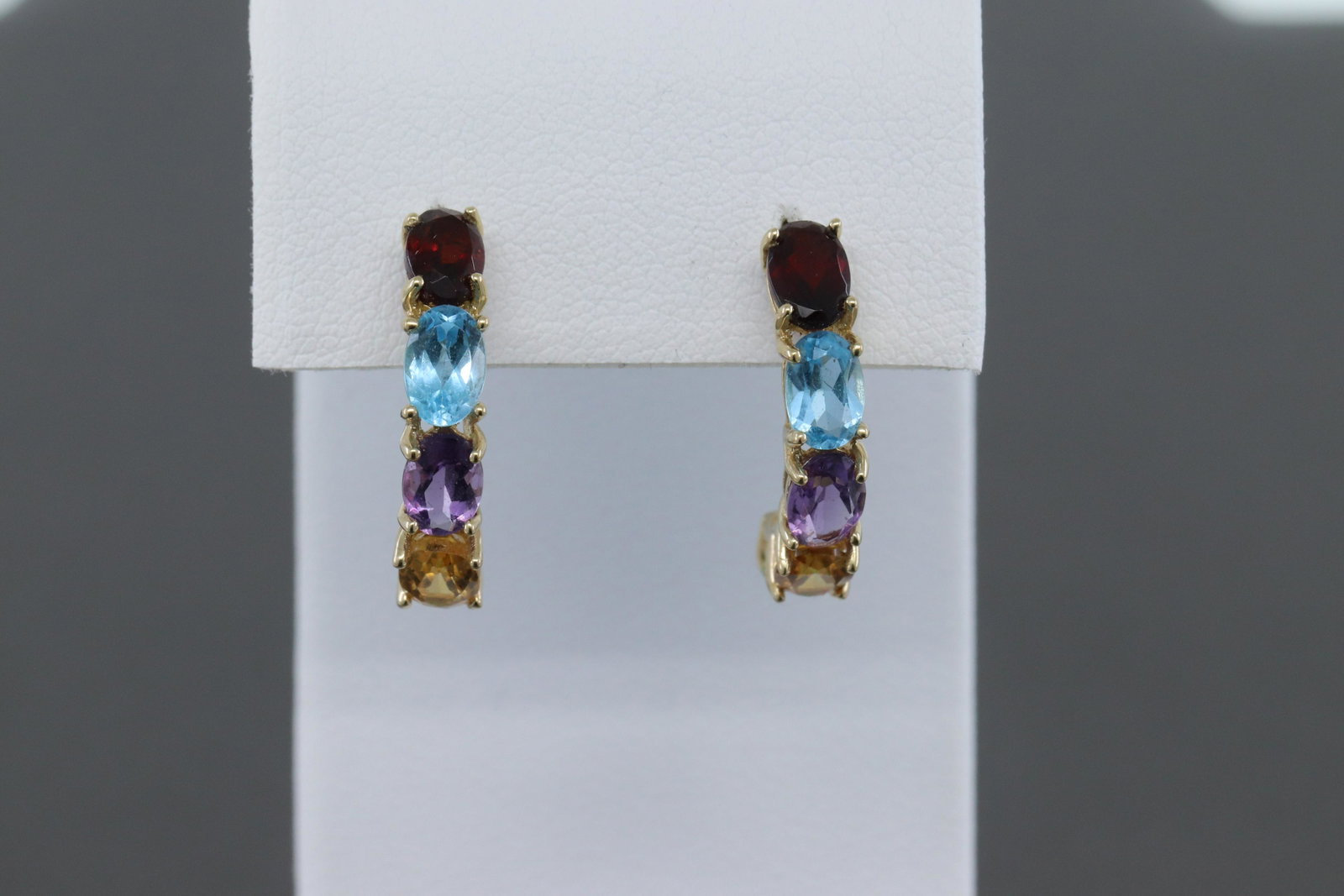 14Kt Multi-Color Earrings: A ladies 14kt Yellow Gold Multi-color earrings. The earring has Peridote, Citrine, Amethyst, Blue Topaz and Garnet stones. Length of earrings about 1.00". Total of 10 Oval shape colored stones. 14kt E