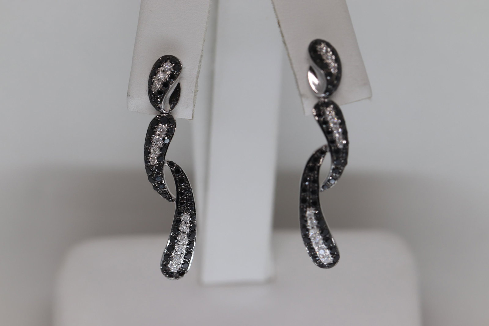14KT Ladies Modern Diamond Earrings (1.33cttw): A ladies 14kt White Gold Diamond earrings. These earrings are modern design. The diamonds weight is approx 1.33tcw (White & Black Diamonds). The earrings length is about 1.25in. These earrings are in 