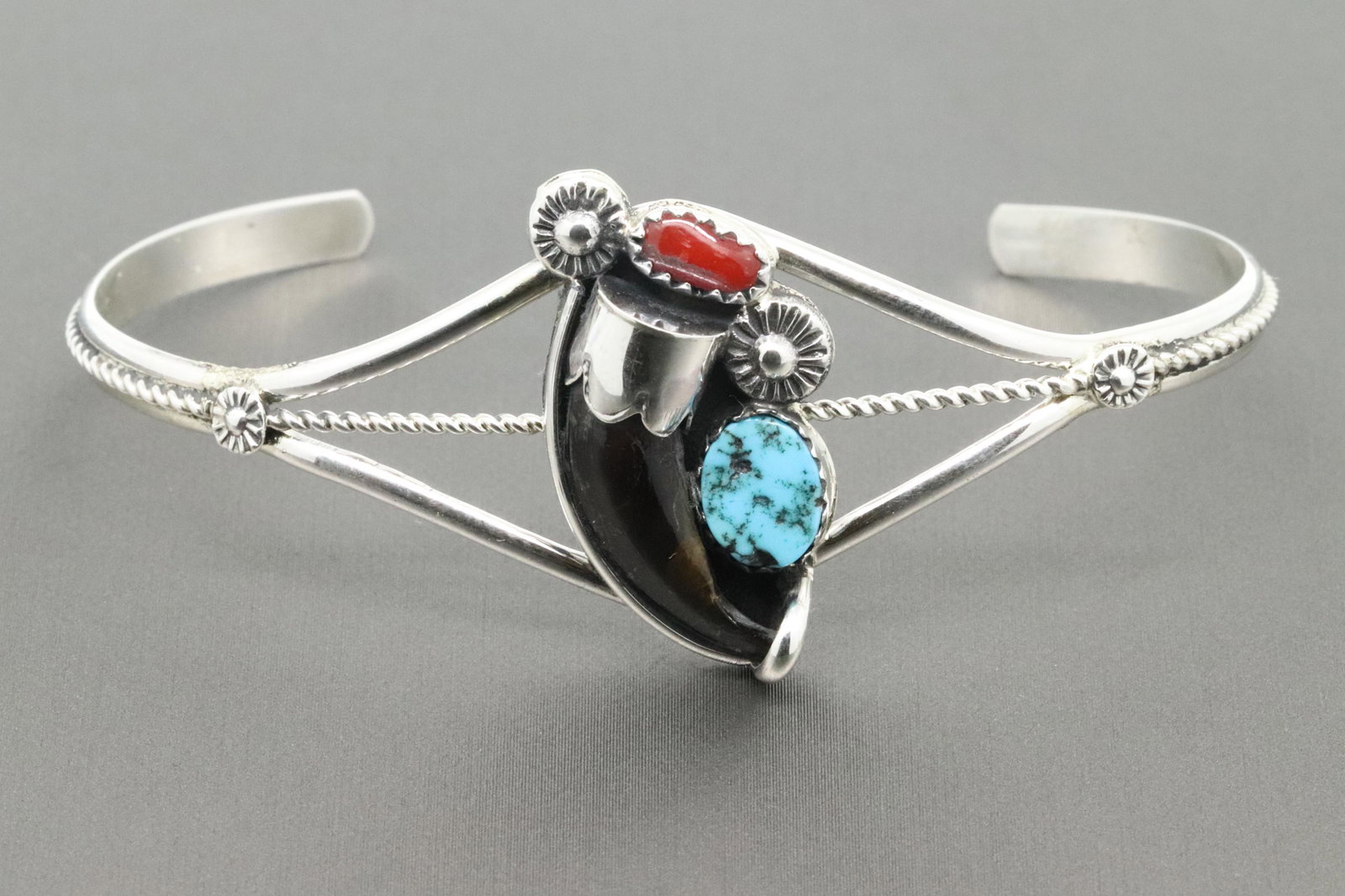 Sterling Silver split shank bracelet with a natural: Sterling Silver split shank bracelet with a natural coyote claw and a free turquoise and coral stone. Top of bracelet measures approximately 1" long by 5/8" wide and tapers down. Made by Navajo artisa