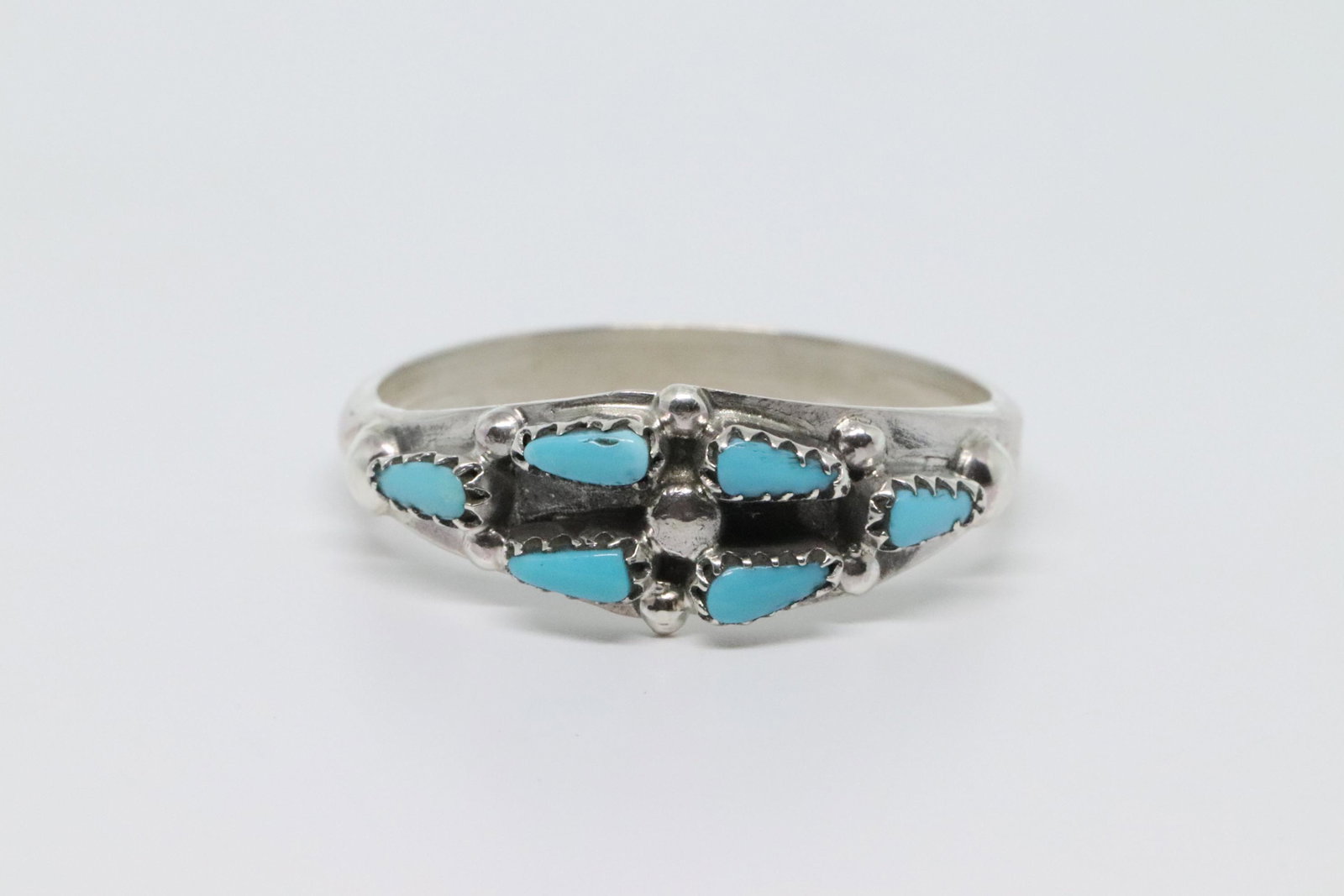 Zuni Turquoise Ring.: This sterling silver ladies ring is made with 6 handcut petty point turquoise stones. It measures just under 1/4" wide and tapers down. Made by Zuni artisan Charles Martinez Sr. ring size 7.