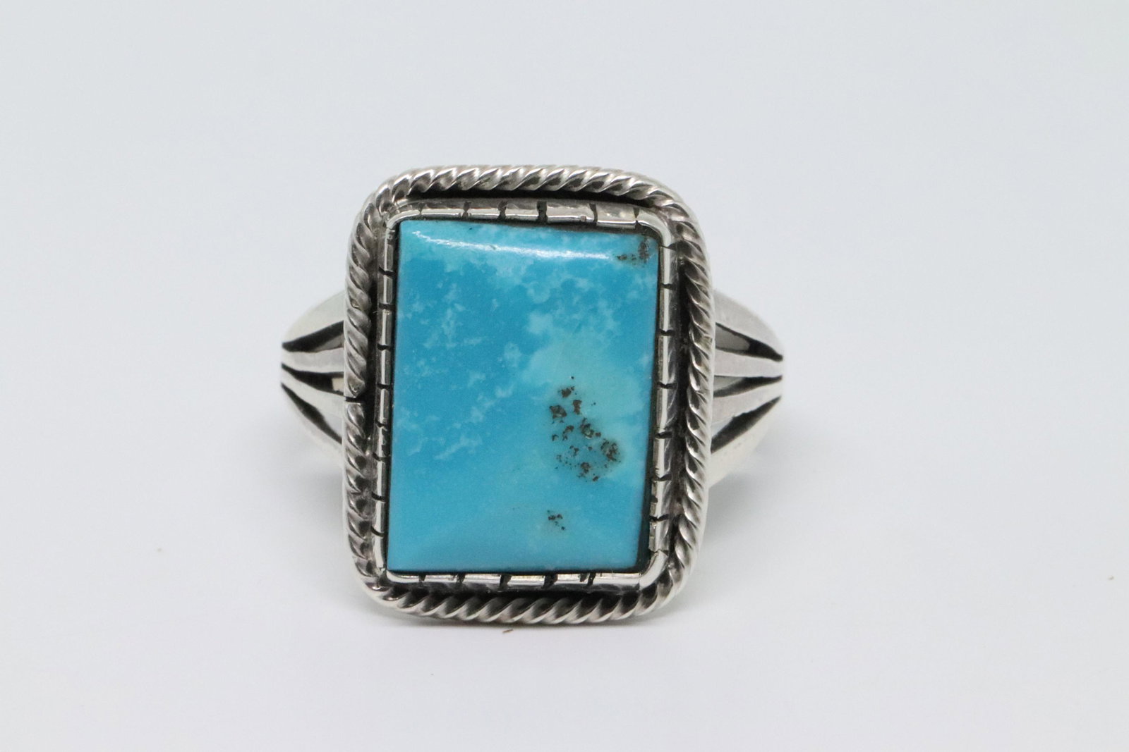 Sterling Silver Mens Navajo Ring.: Sterling silver four split shank, stamped at the bottom, mens Turquoise ring with a handcut rectangle shape turquoise stone and a twist wire border. Top of ring measures just over 3/4" long by 5/8" wi