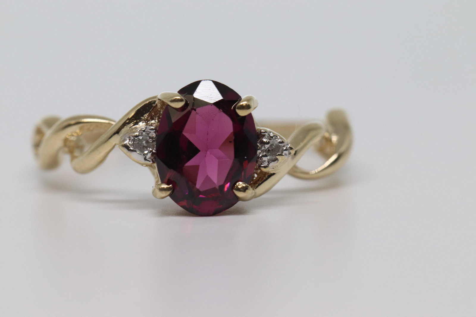 Ladies Diamond & Garnet Ring: A ladies 10kt Yellow Gold Diamond Ring. The ring has a oval shape Garnet stone in the center.The center stone measures 8.00x6.00mm. The color of the stone is purplish. There are a total of 2 round dia