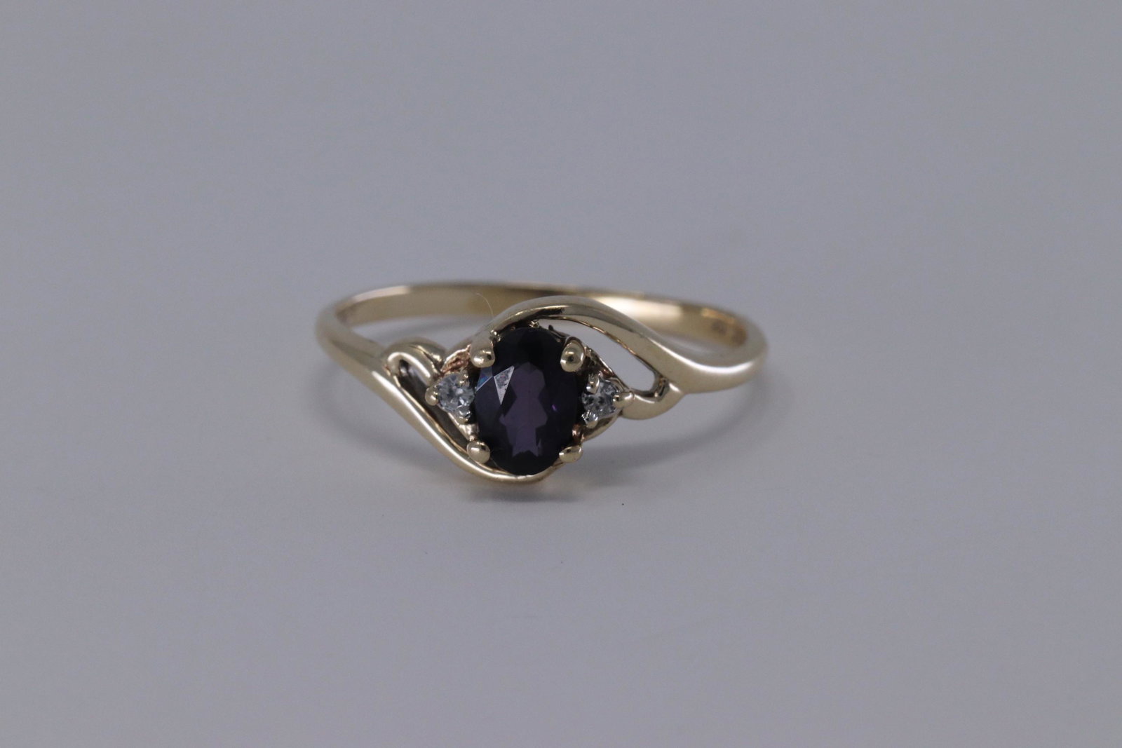 Ladies Diamond and Amethyst Ring: A Ladies 10kt Yellow Gold Diamond ring with a Amethyst stone in the center. There are a total of 2 round diamonds set on the sides and an oval shape amethyst stone on the center. Rings size: 6.00. SKU