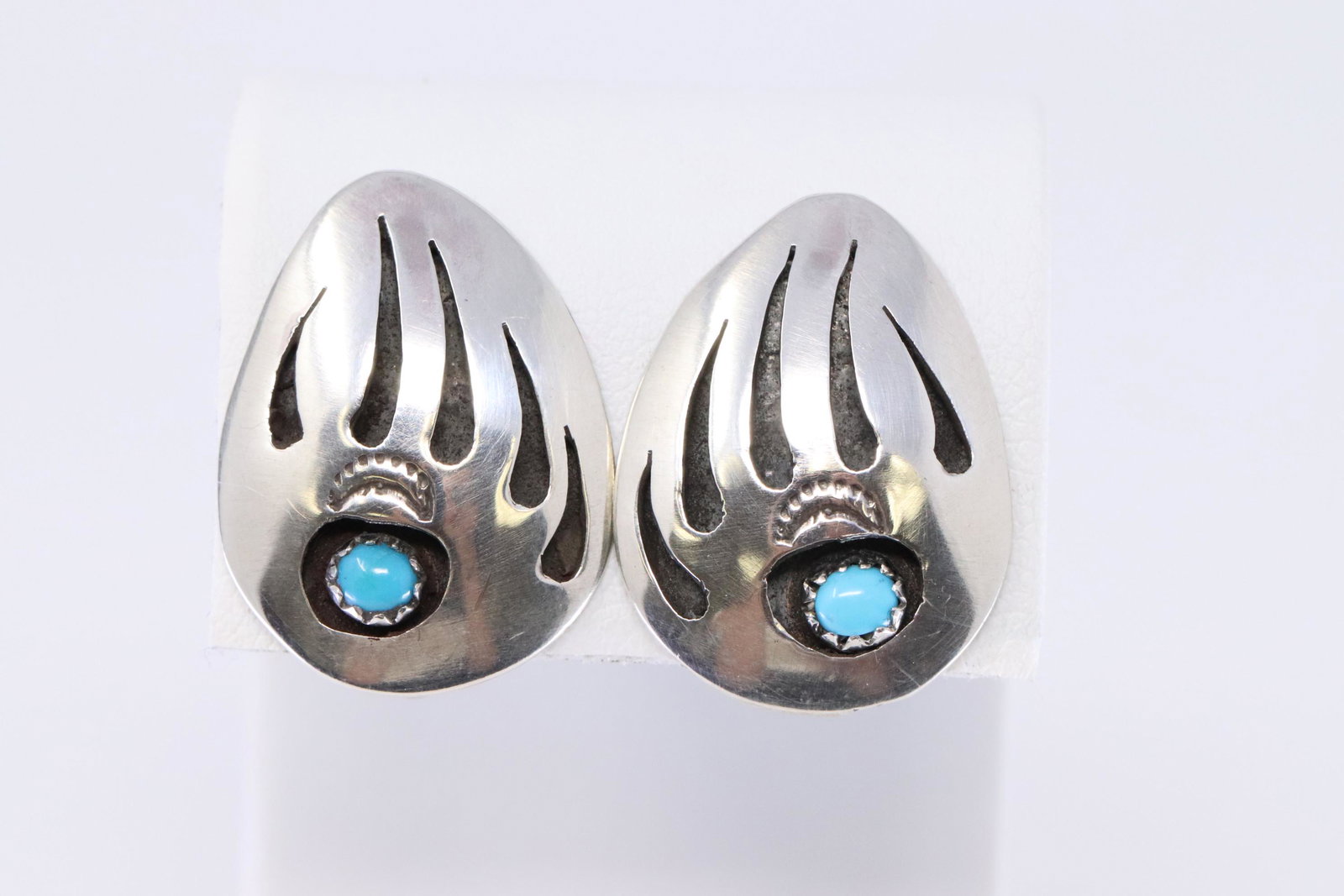 Sterling Silver Navajo Earrings.: Sterling silver badger paw shadow box clip earring with a free form synthetic turquoise stone. Earring measures about 1" long by 3/4" wide. Navajo crafted by Ervin Begay.