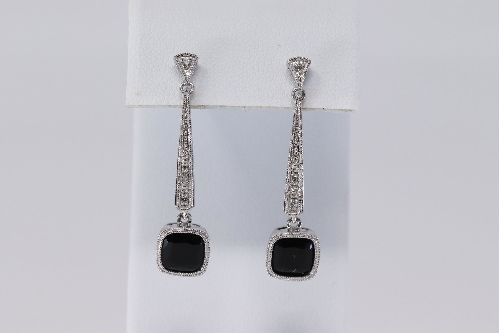 Ladies White Gold Diamond-Onyx Earrings: A ladies White Gold Diamond dangling earrings. The earrings has a total of 2 Squared Black Onyx stones. Earrings length: 1.50". Total weight 3.80 grams.