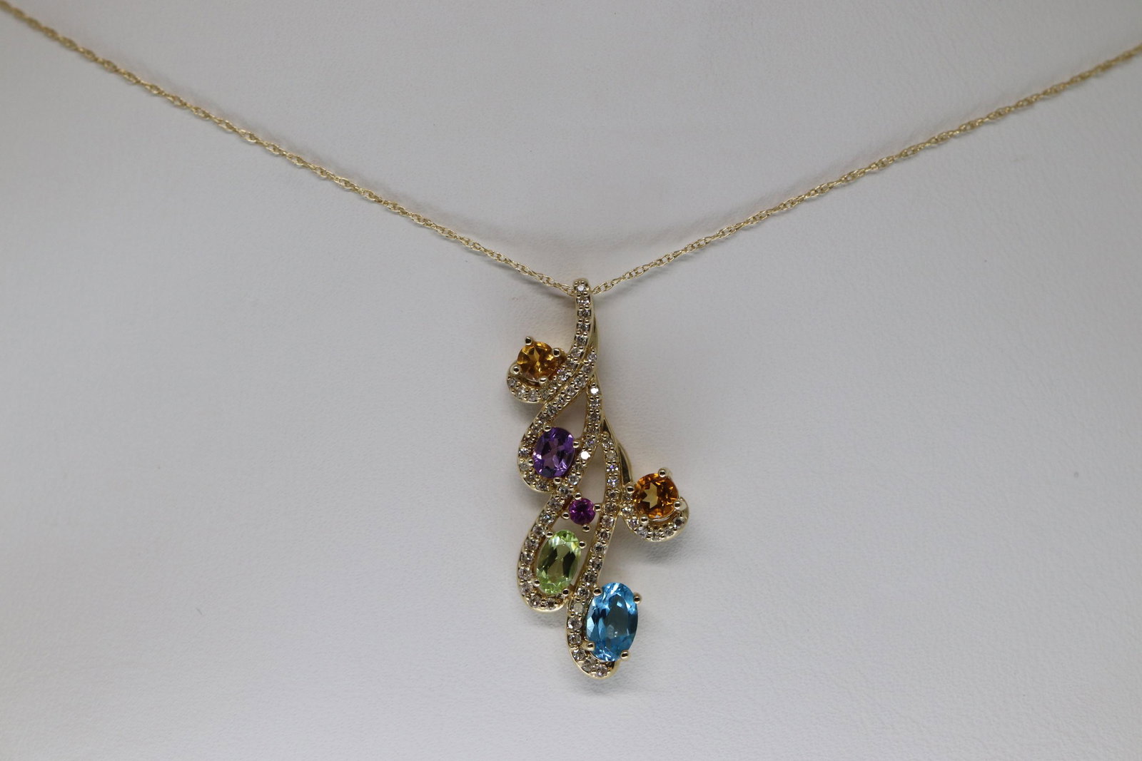 14kt Semi-Precious Diamond Necklace: A 14kt Yellow Gold Semi-precious stone with round brilliant diamonds. The pendant has a total of 6 colored gemstones and 73 round diamonds. Total diamond weight is 0.25twc. Length is about 18-20in.