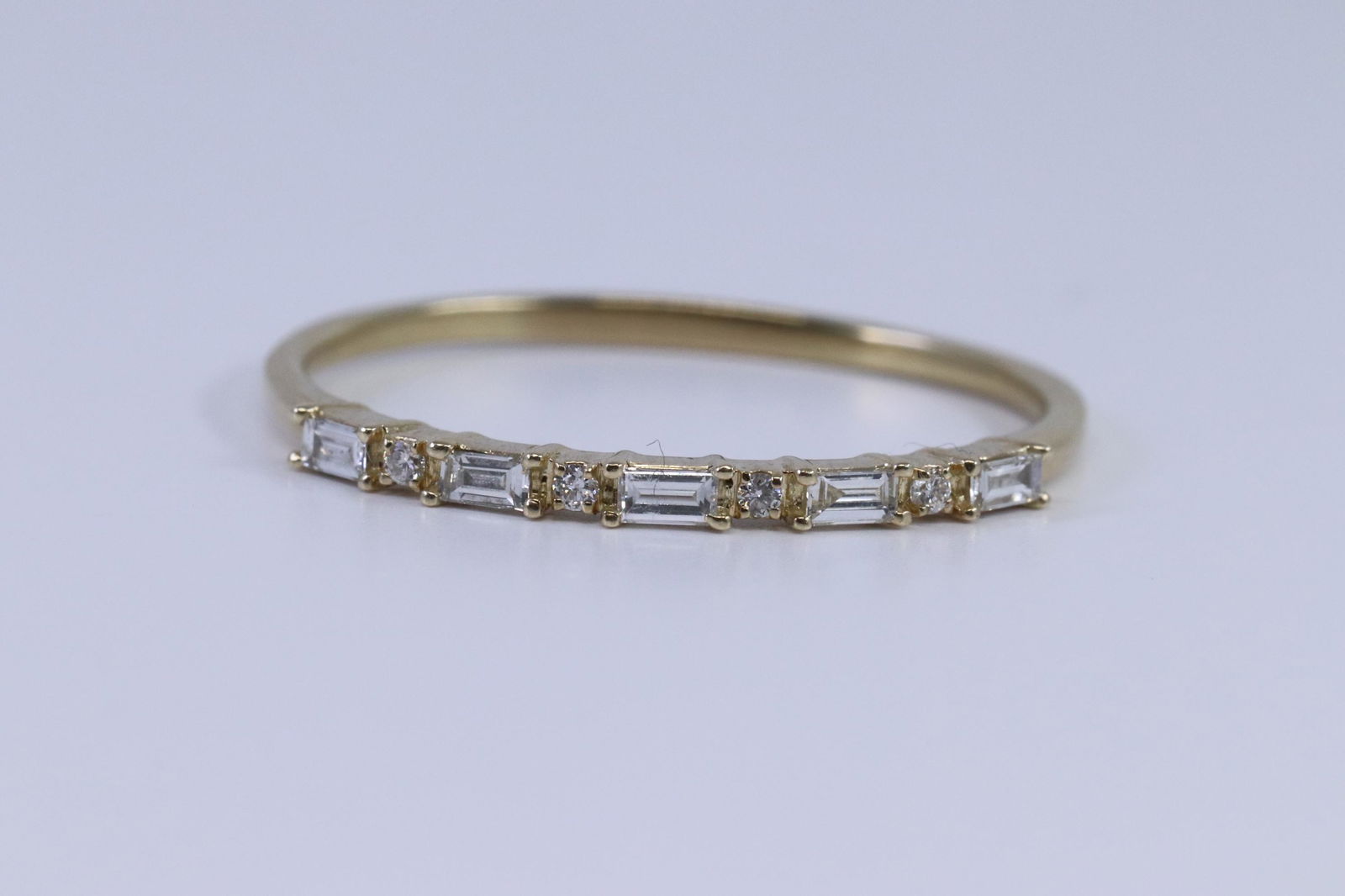 14Kt Ladies Diamond Stackable Ring: A ladies 14kt Yellow Gold Diamond Ring. Ring has a total of 9 diamonds weighting approx 0.15ctw. Ring size: 10.00. Total weight: 1.50 grams.