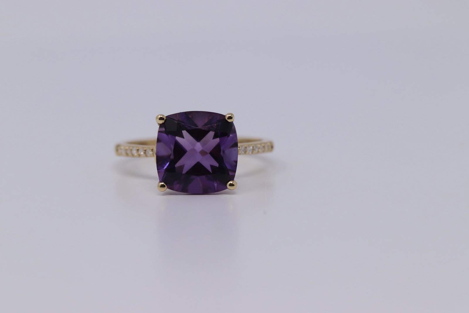 Ladies Yellow Gold Diamond/ Amethyst Ring: A ladies Yellow Gold Diamond ring with an Amethyst stone set on the center. Diamonds weight 0.08ctw. Ring size: 6.50.