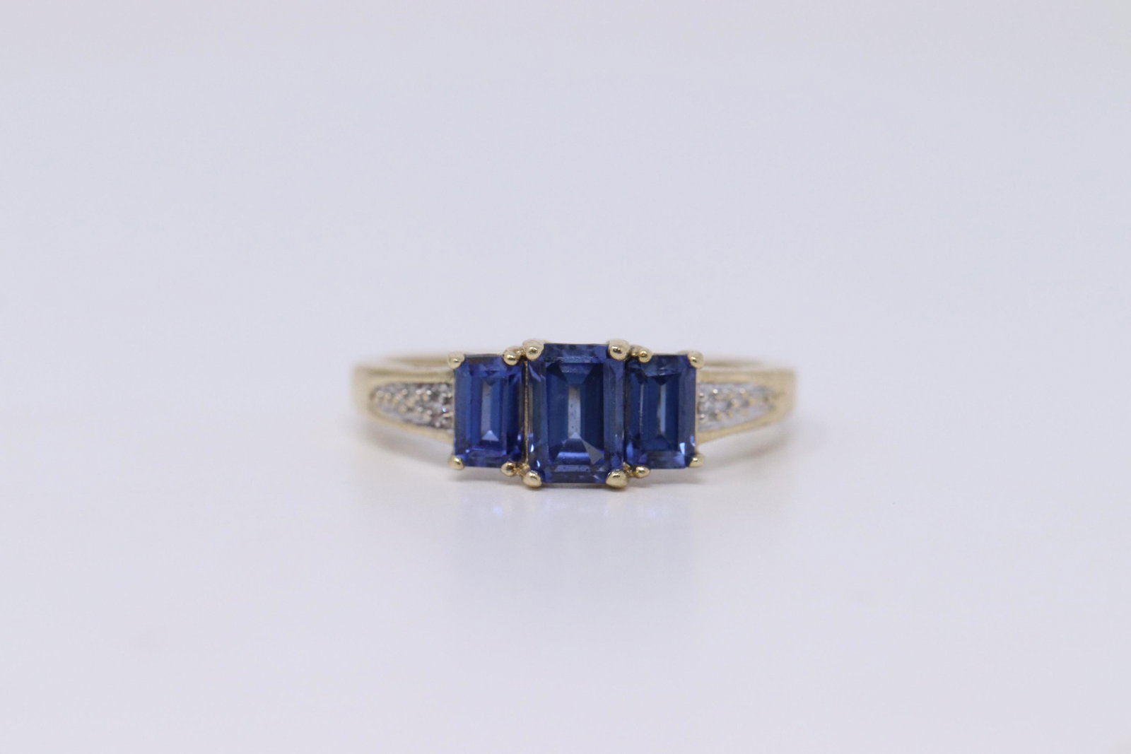 Ladies Diamond/Tanzanite Ring: A ladies Yellow Gold Diamond ring. Ring has diamonds on the sides and 3 rectangular Tanzanite stone in the center. Ring size: 6.25. Total weight: 2.20 grams.