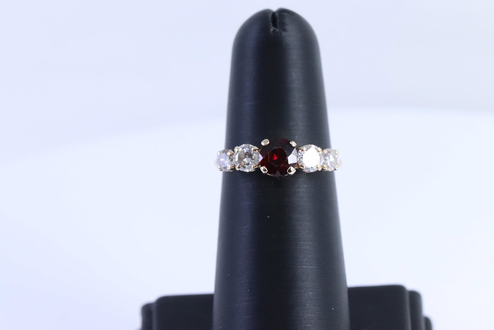 14KT Ladies Diamond Ring| Round Garnet: A ladies 14kt Yellow Gold Diamond ring. Ring has a total of 4 round brilliant diamonds and 1 round Garnet stone in the center. Diamonds weight approx 0.80cttw. Clarity: VS1-VS2, color: F. Ring size: 7