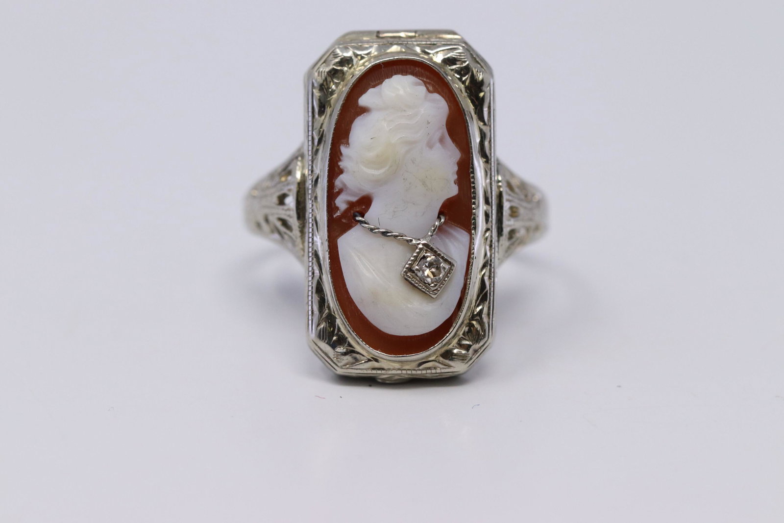 14Kt Art Deco Diamond Cameo Filigree Locket Ring: A ladies 14kt White Gold Art Deco Filigree Diamond ring. The 1930's 14k white gold filigree ring contains a carved shell cameo of a woman in profile. Ring is an Cameo ring with a round diamond stone i
