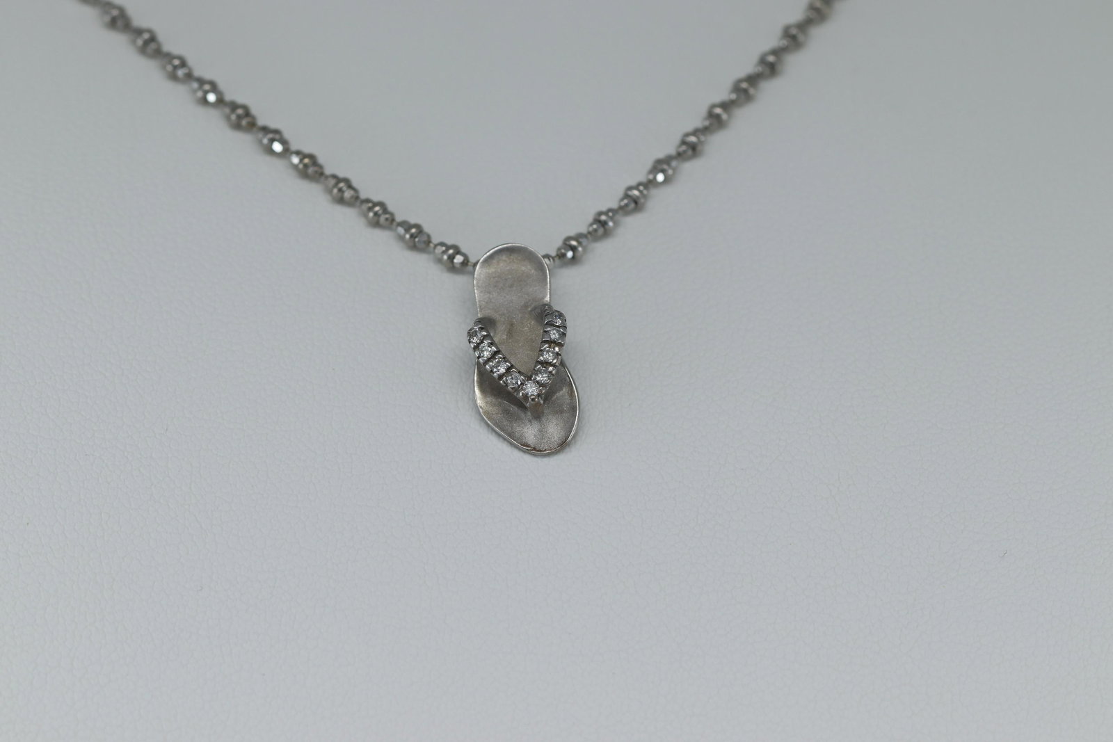 14K White Gold Diamond Sandal Necklace: This is a Ladies 14K White Gold Diamond Sandal Pendant with a Necklace. This is a sandal charm that has 9 round brilliant diamonds set on the strap of the sandal. SKU:DIDH7UQ
