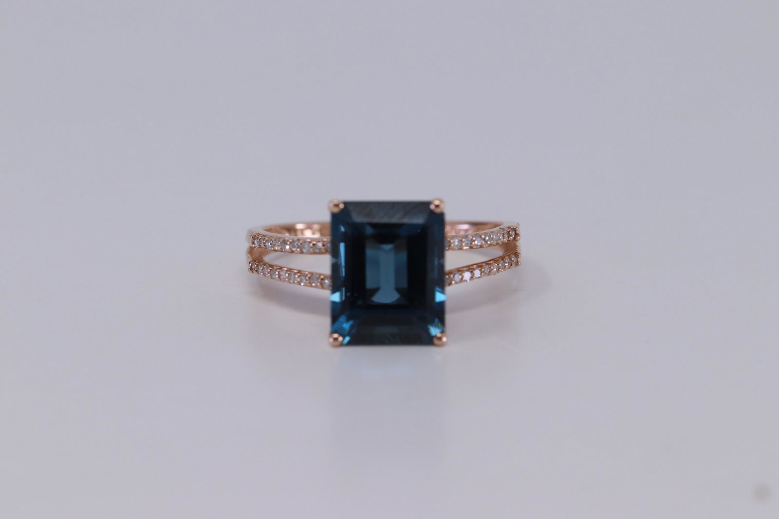 14Kt Rose Gold Diamond/London Blue Topaz Ring: A ladies 14kt Rose Gold Diamond ring. Ring has a London Blue Topaz stone in the center and round diamonds set on the sides. Diamonds weight 0.10ctw. Ring size: 7.00.