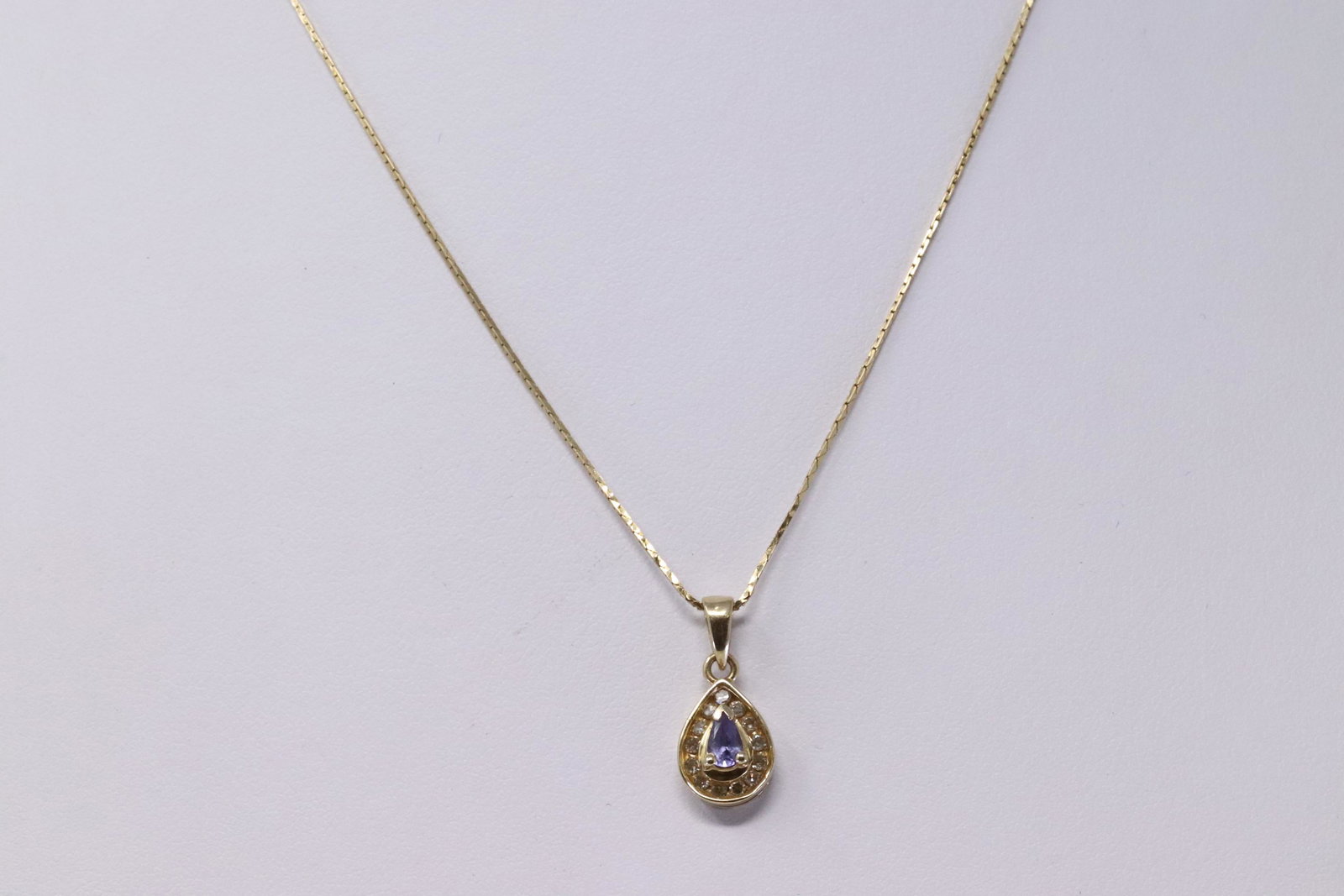 14Kt Diamond/ Tanzanite Necklace: A ladies 14kt Yellow Gold Diamond pendant. Pendant has a total of 13 round diamonds set around Pear shape Tanzanite stone in the center. 14Kt Necklace length: 17.00in. Total weight: 2.60 grams.