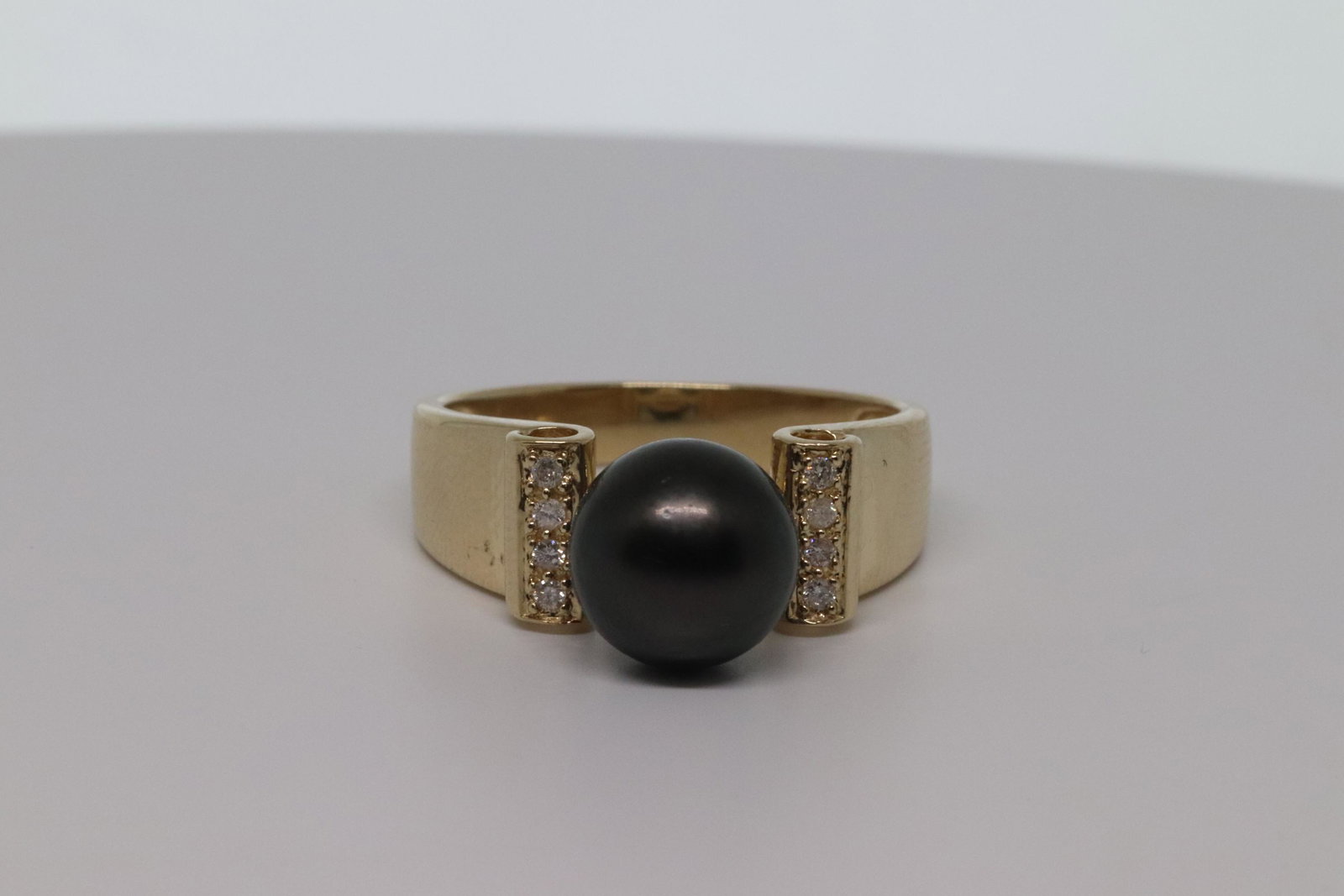 14Kt Ladies Pearl & Diamond Ring: This is a beautiful 14kt Yellow Gold Diamond Ring. The ring has a total of 8 round diamodns on the sides. The ring has a Black Pearl on the center which measures 8.80mm. Ring size is 7.00. SKU04IUQB7