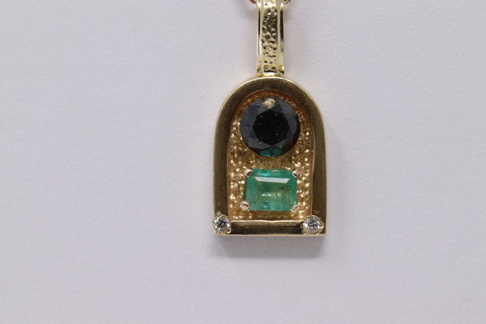 14kt Yellow Gold Diamond, Black Diamond & Emerald: A ladies 14kt Yellow Gold Diamond pendant. Pendant has a round Black Diamond in the center, Emerald stone also in the center of the pendant and 2 round diamonds on 2 corners. Black Diamonds measures: 