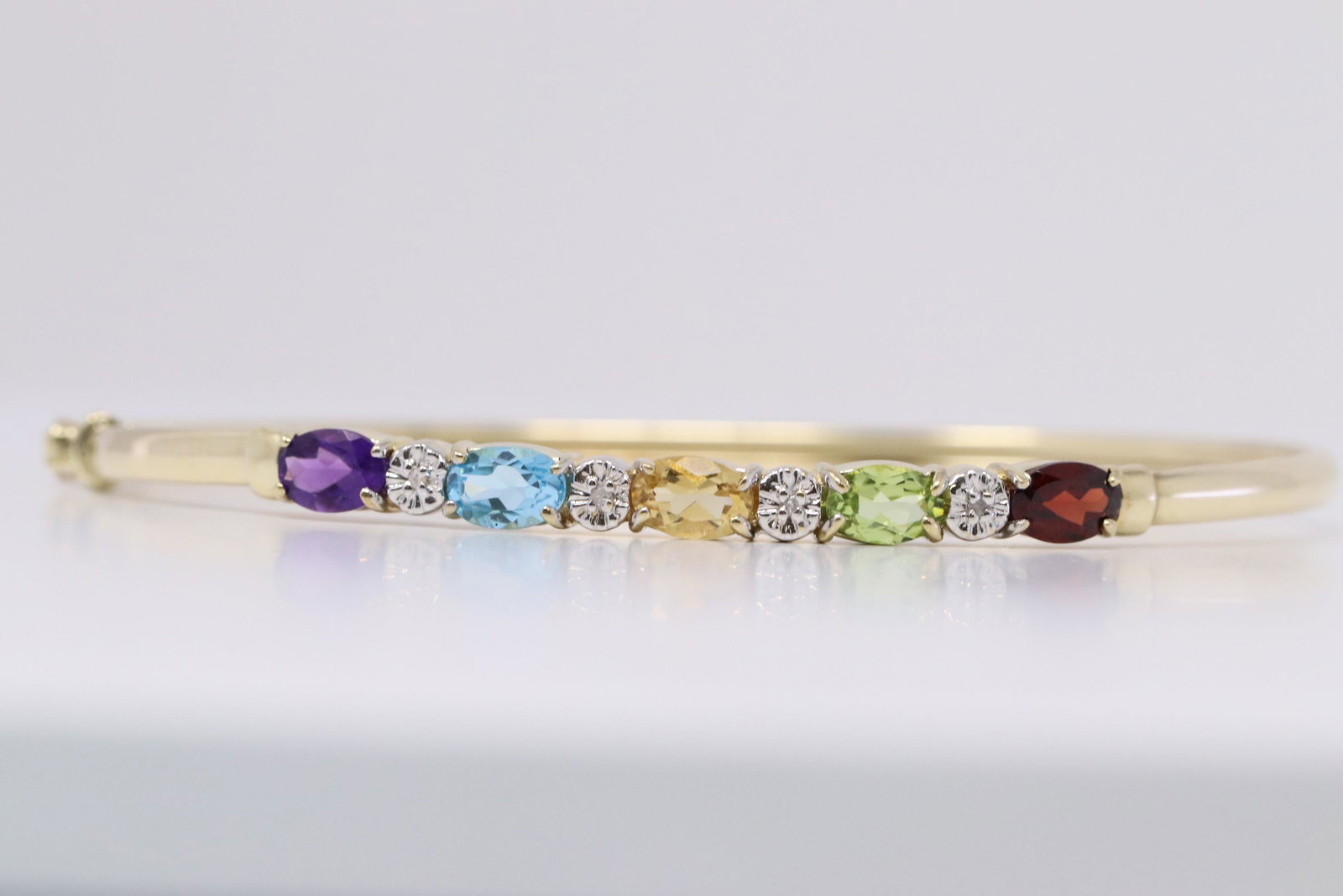 Ladies Multi Color Bangle w/ Diamonds: A ladies Yellow Gold Diamond bangle. Bangle has multi color stones such as: Amethyst,Topaz,Citrine,Peridot and Garnet. Total weight: 5.60 grams.