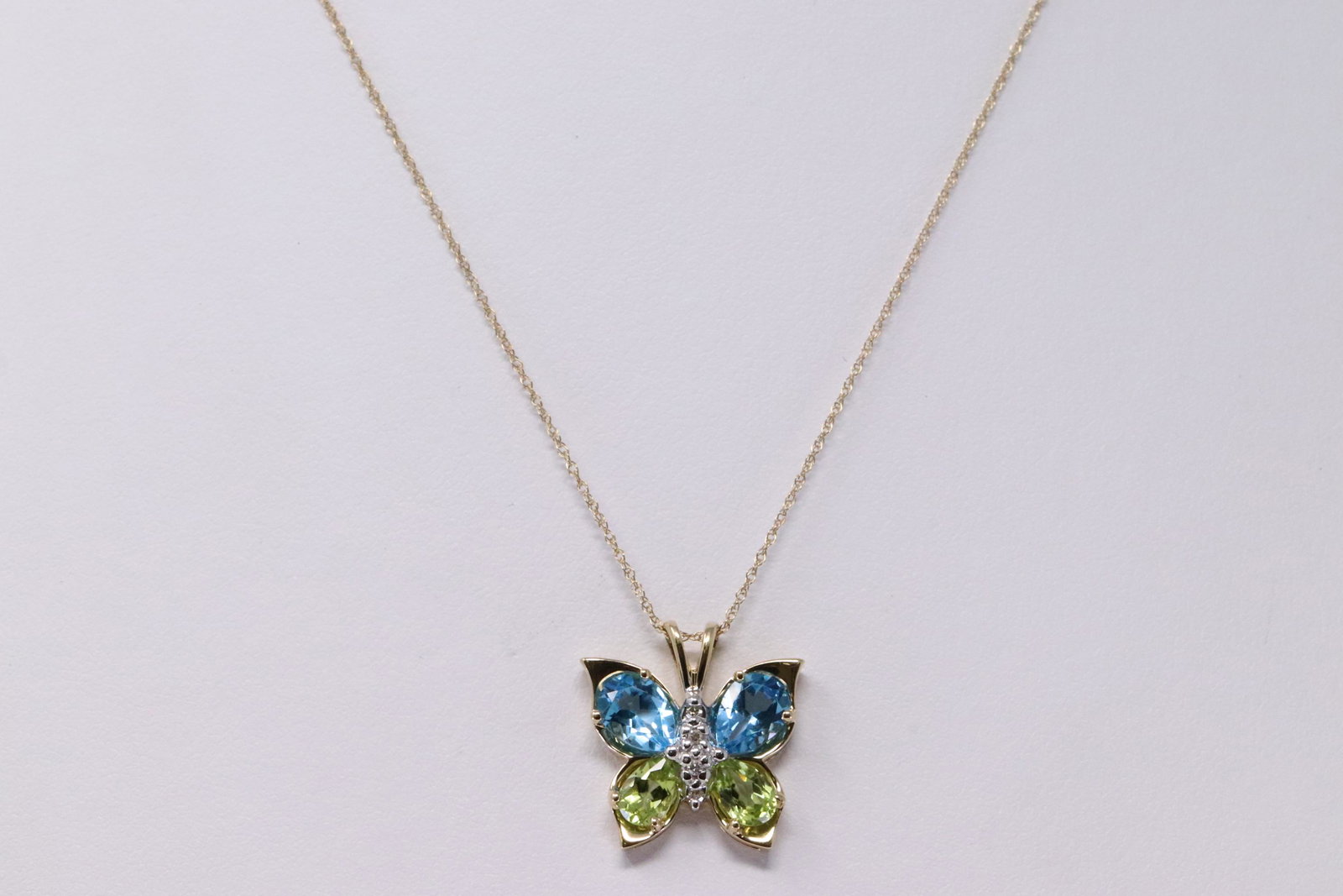 Ladies Diamond/Blue Topaz/Peridot Buttterfly Pendant: Ladies Yellow Gold Diamond Blue Topaz, Peridot Butterfly Pendant. Pendant has a total of 4 Diamond in the Center. 2 Blue Topaz and 2 Peridot on de Sides. Necklace Length: 18.00". Total weight: 2.91 gr