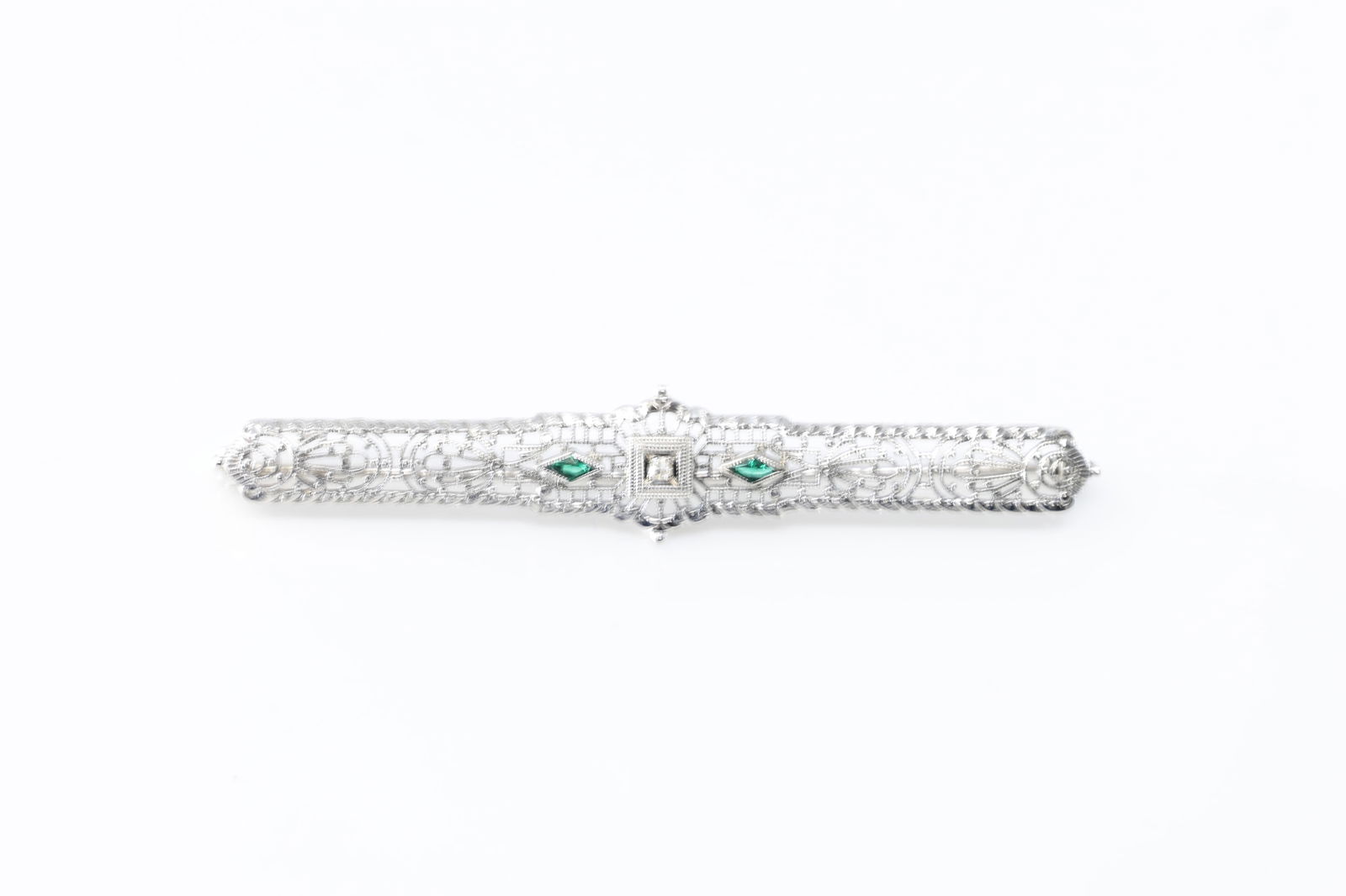 Art Deco Emerald & Diamond Pin / Brooch 14Kt.: 14Kt White Gold Art Deco Emerald & Diamond Pin / Brooch. brooch showcases intricate filigree work, adorned with delicate green emerald's gemstones with a cut diamond. Its timeless design makes it a