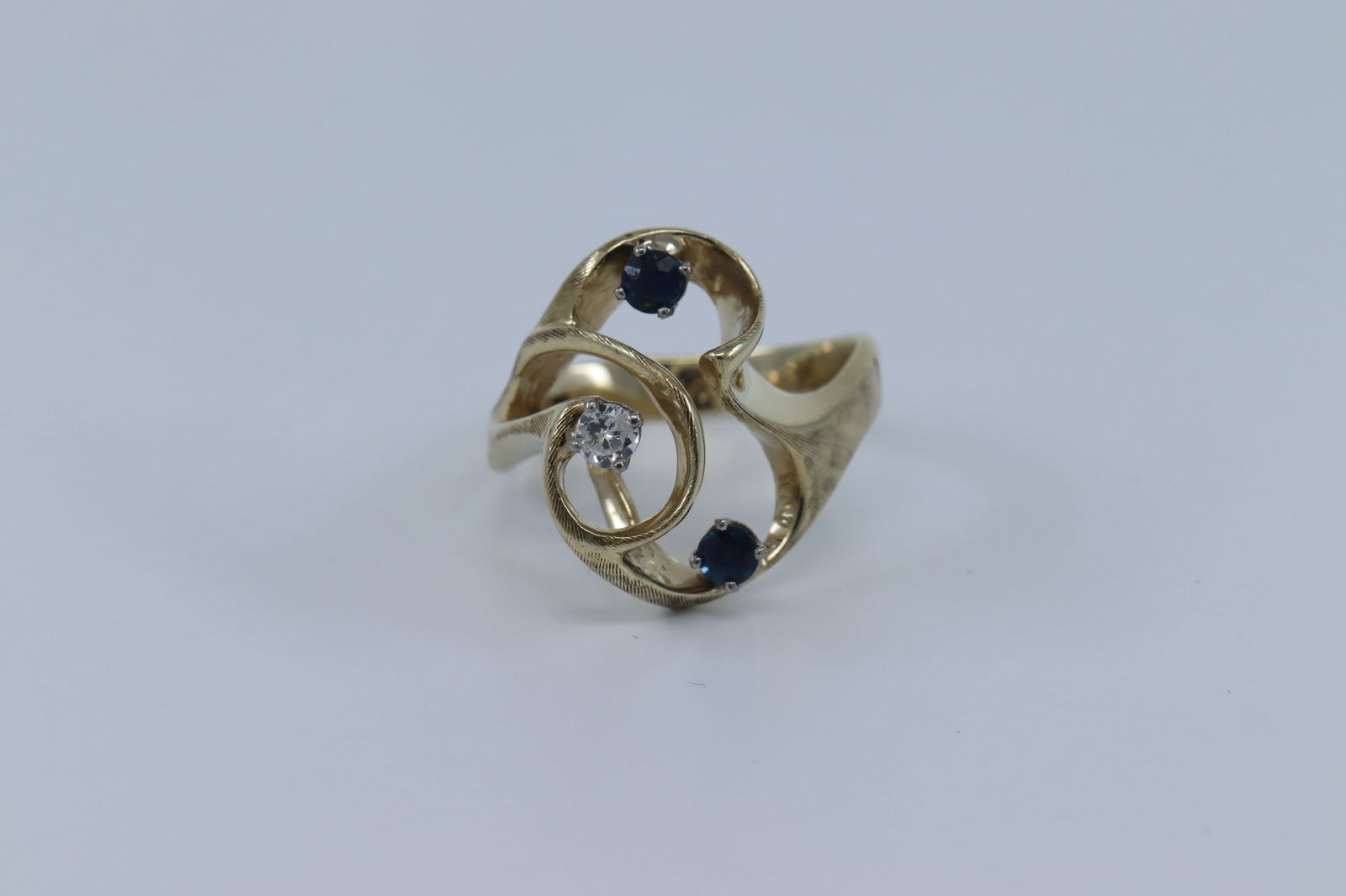 14Kt Yellow Gold Diamond w/ Round Sapphires Ring.: A 14Kt Yellow Gold Diamond ring. The ring has a round brilliant diamond on the center and 2 round blue sapphires on the sides. The ring size is 7.50. Total weight is 5.60gr.