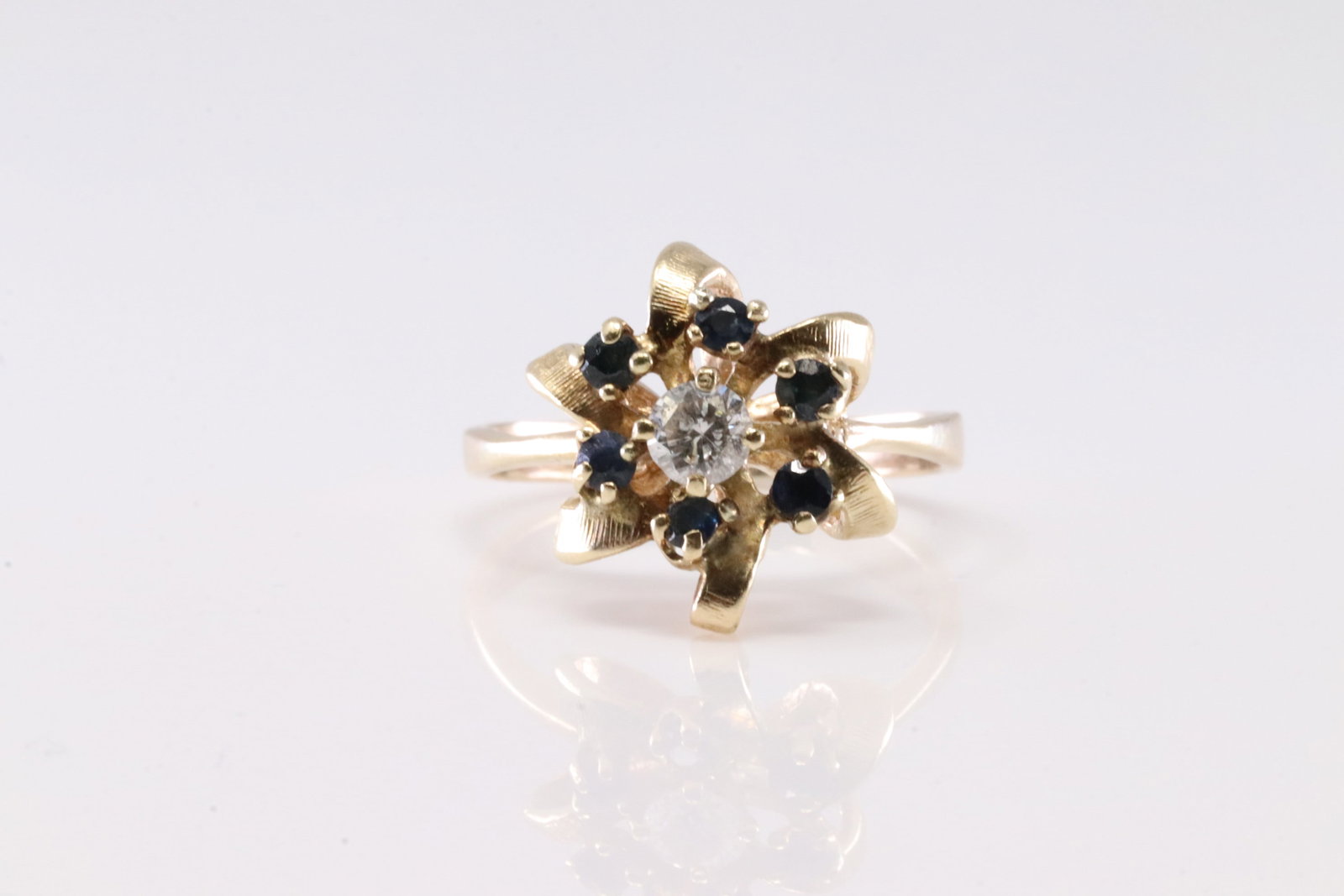 Sapphire & Diamond Ring 14Kt.: Ladies 14Kt Yellow Gold Sapphire & Diamond Ring. This Charming Ring has Flower Design With 6 Blue Sapphire Gemstones & Solitaire Round Diamond In The Center. Diamond Approx Weight: 0.25ctw. Ring