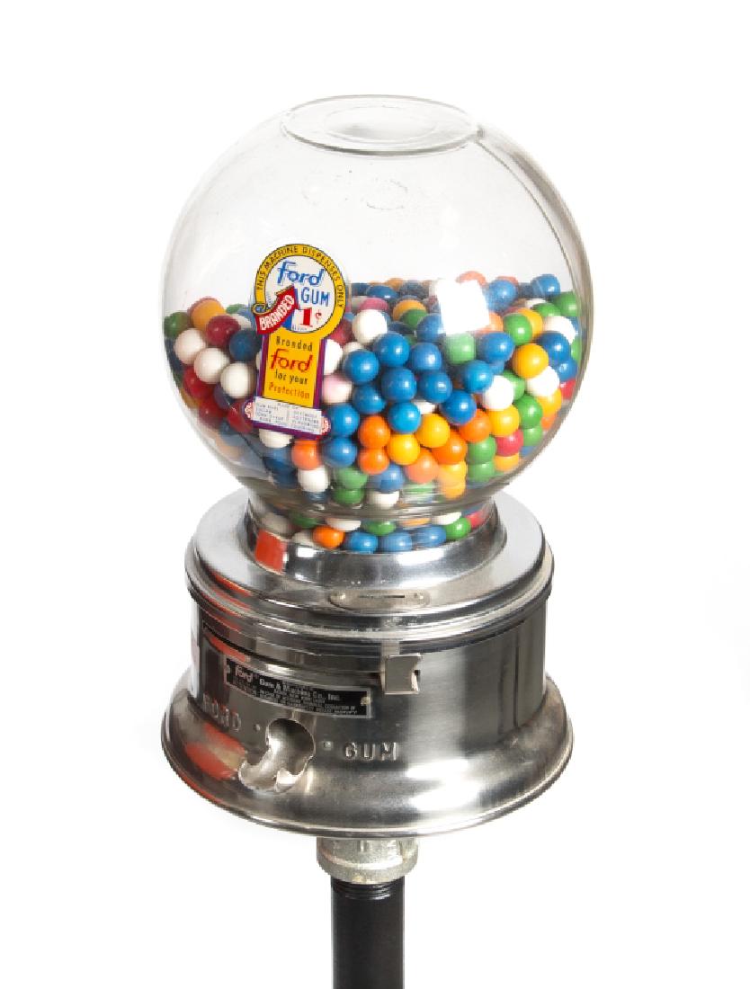 A vintage gum pack and gumball machine on stands: The red enameled and plastic Wrigley's gum pack dispenser with turn knob operation and the second, a Ford glass dome 1 cent gumball machine with slide mechanism. Greatest height 49in.