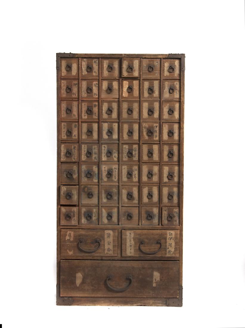 A Japanese kiriwood apothecary cabinet: With wrought iron mounts and paper labeled drawers. 32in. H x 8 3/4in. W x 16in. L. (WAT 48)