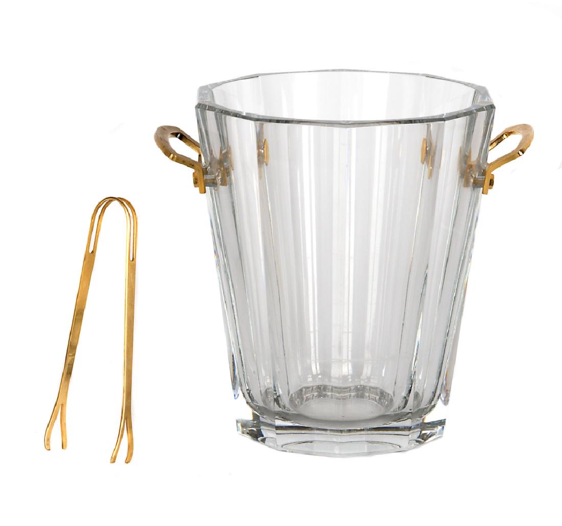 A Baccarat wine cooler: Tapered cylindrical shape with fluted cutting and brass handles. Along with an associated pair of brass tongs. 9in.H x 10in W.