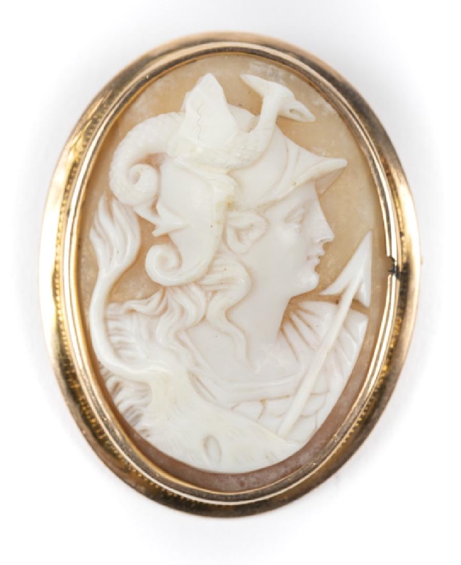 A shell cameo of the goddess Nike, 10k pin: Featuring an oval shell cameo of the goddess Nike, set in a 10k yellow gold frame measuring approximately 39.9 x 31.2 mm. Gross weight: 8.0 grams. Condition: break in bezel near cameo.