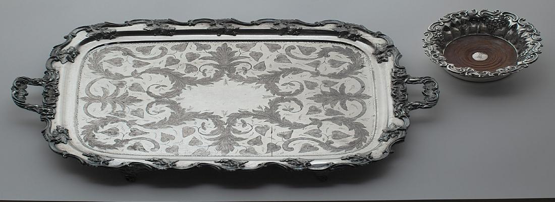 A Sheffield plate tea tray and wine coaster: The tray rectangular with engraved face, footed and with handles, L. 27 1/2 in; with a Sheffield plate large wine coaster with wooden base, crest.