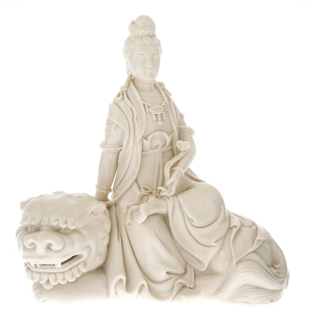 A Chinese Dehua porcelain figure of Guanyin: 20th century Depicted sitting in lalitsana upon a lion and clasping a ruyi scepter in her left hand. Height: 8 7/8in.