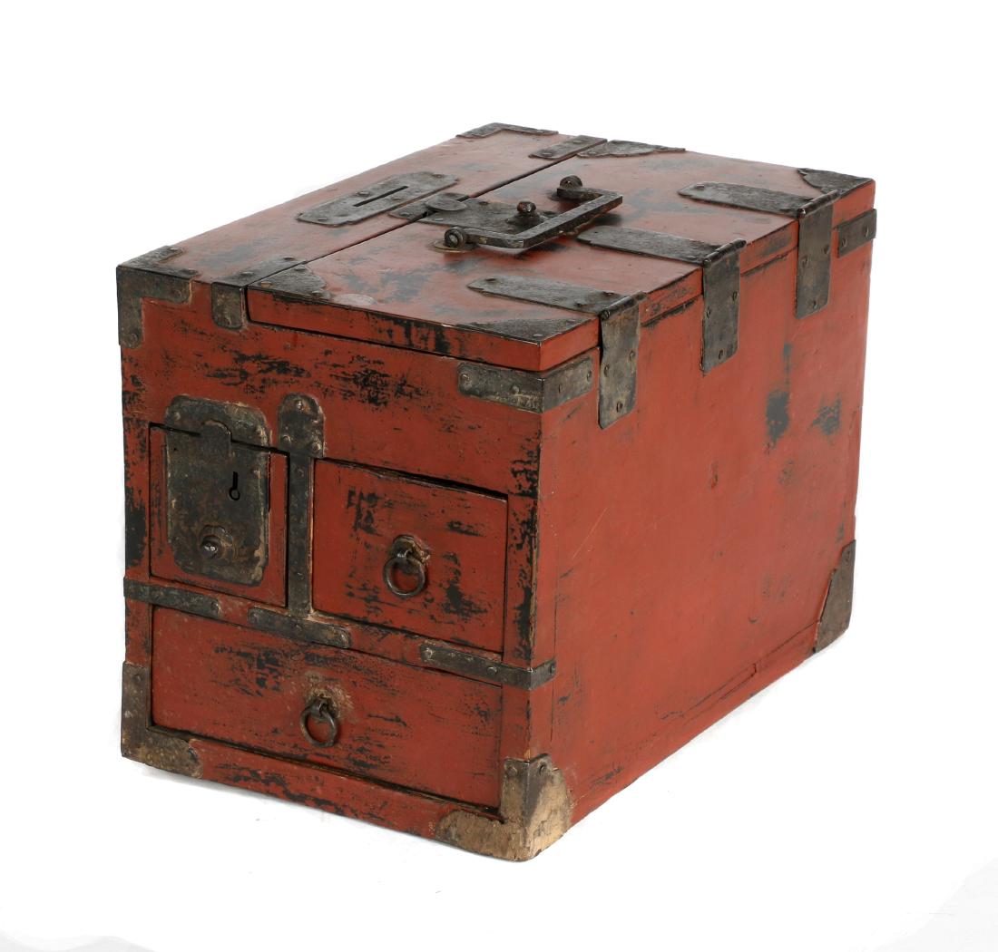 A Japanese lacquered wood merchant's chest: Meiji period Painted in red lacquer with three drawers and a hinged lid to reveal a writing instrument compartment, cast iron fittings. 9 1/8in. H x 8 1/4in. W x 12 1/2in. L