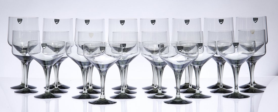 Orrefors Rhapsody stemware: Executed in smoke gray, a service for 8 comprising champagne coupes, water goblets and wine goblets, some with sticker labels, with tallest 7 1/4 in. (18.25 cm) high; (24 items). Condition: O