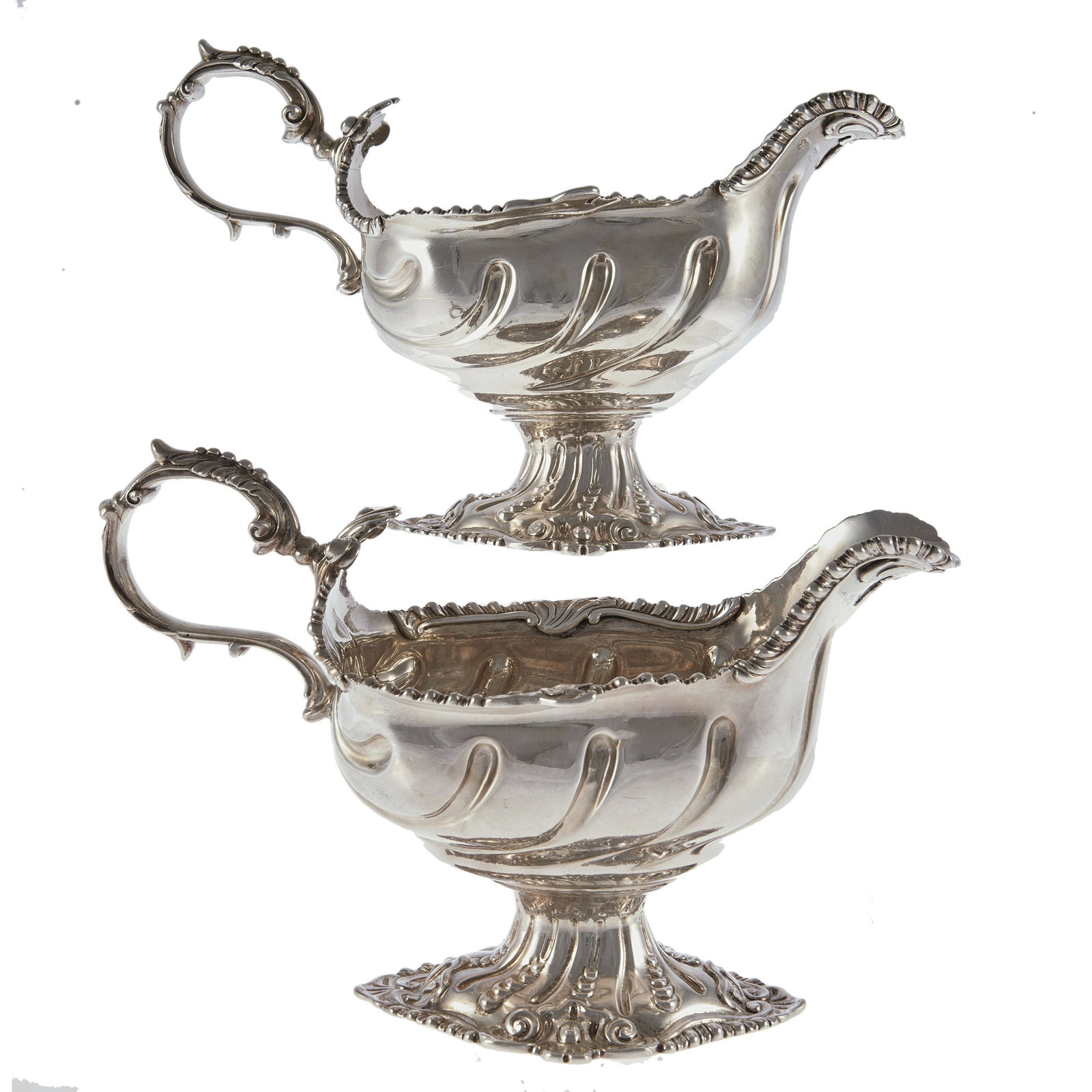 A pair of George III sterling silver sauce boats: London, 1766, makers mark rubbed, executed in the Rococo taste, having an oval form, the rim and flared spout with gadrooned details, the scrolled handle with foliate decoration, the body with swirled