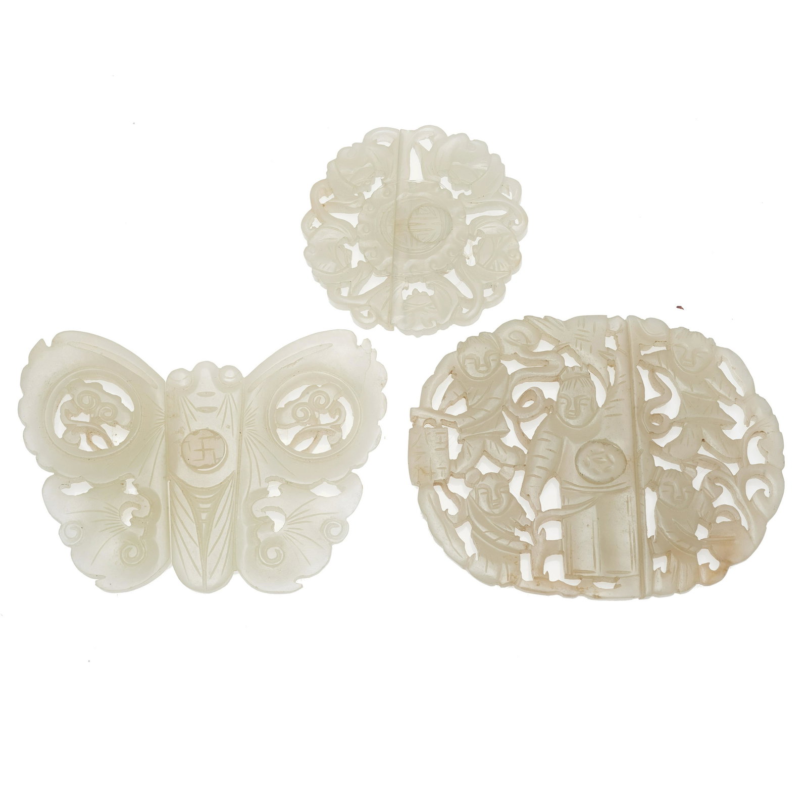 Three Chinese jade openwork belt buckles: Qing dynasty Comprising a butterfly form buckle, an oval form buckle of five figures, and a circular buckle of five bats centering the longevity character. Widest: 2 11/16in.