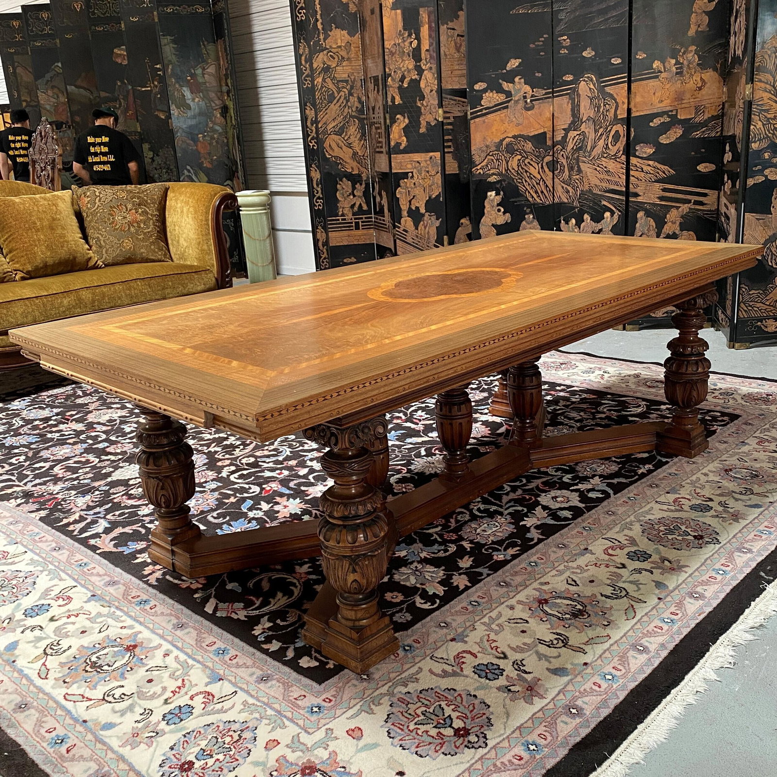 Baroque Style Refectory Table: The rectangular top inlaid with a central clover leaf within flame veneer panels and banded inlay, raised on bold acanthus carved baluster supports joined by X stretchers, with two leaves. 30in. (76cm