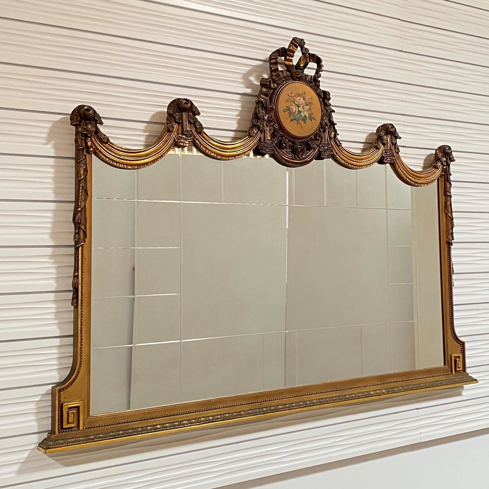 Rococo Style Mirror: The crest carved and ribbon banding issuing tassels and lambrequin centering aÂ rectangular plate framed with mirror tiles above a leaf banding. 60in. (152cm) h. 80in. (202cm) l.