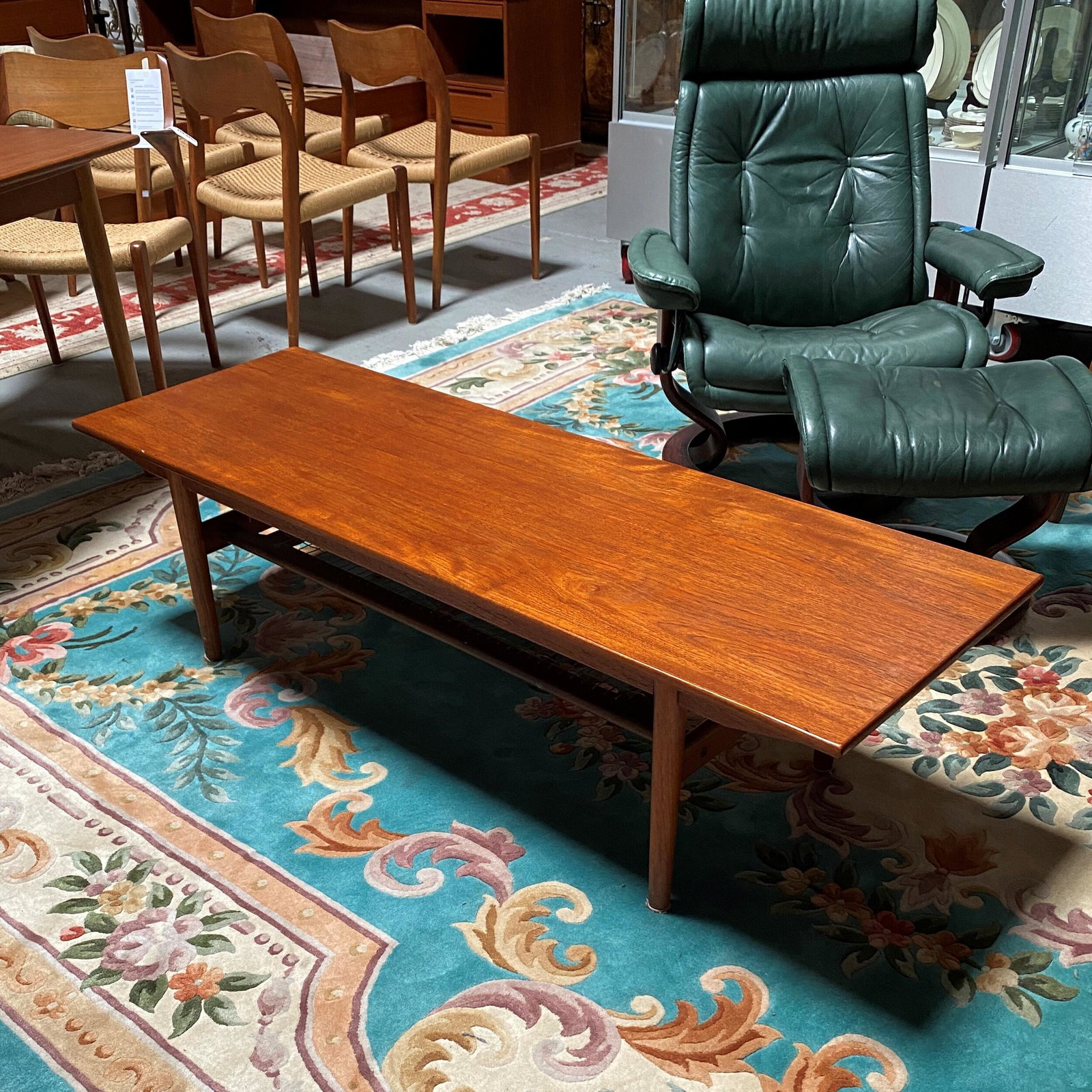 Hovmand Olsen for Jutex Coffee Table: Scandinavian Modern teak coffee table with woven magazine shelf. Stamp underneath reads: Jutex Made in Denmark designed by Hovmand Olsen. Condition: fair with moderate areas of wear. Netting on wo