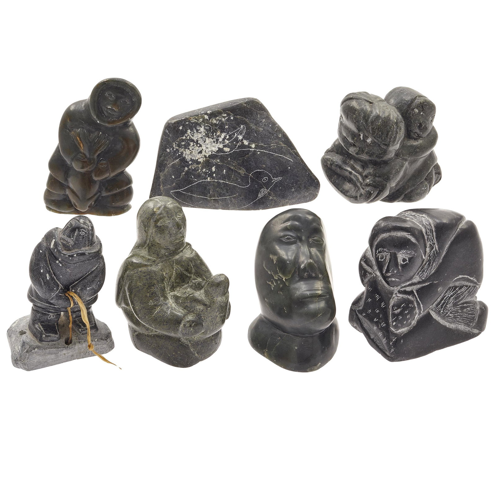 Seven Inuit Stone Carvings: Comprising five daily life figures, a bust of a bald man and a double-sided stone etching depicting nesting birds; each carving signed on the base, five carvings with the Igloo sticker. Widest: 4 7/